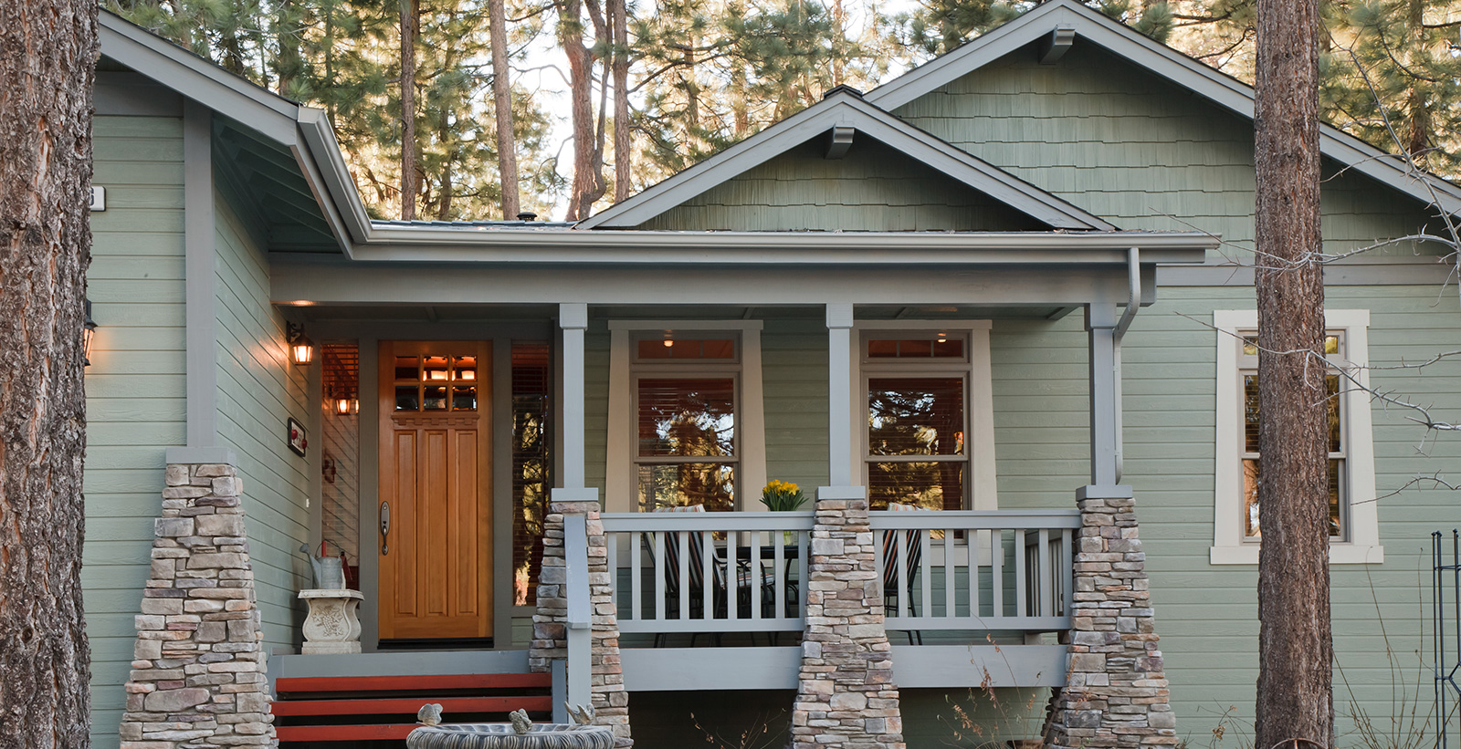 Craftsman themed house with green walls, gray trim, and brown door.