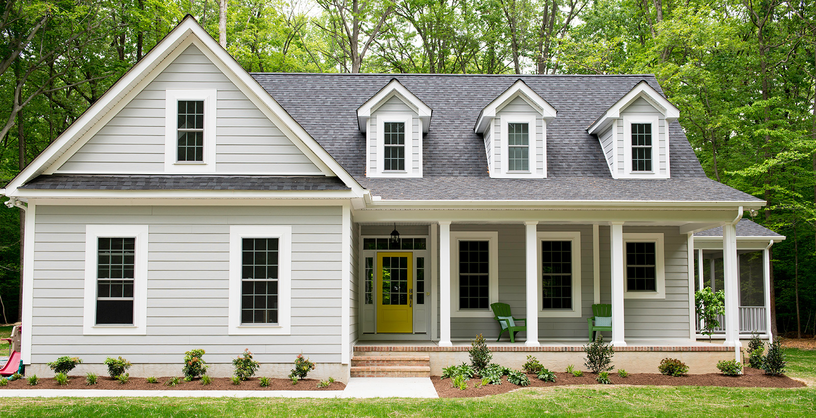 Farmhouse themed cottage house with light gray walls, white trim, and yellow door.