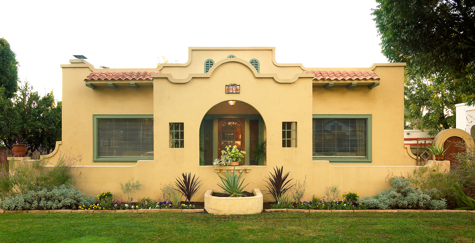 Spanish mediterranean themed house with yellow walls, and green trim.