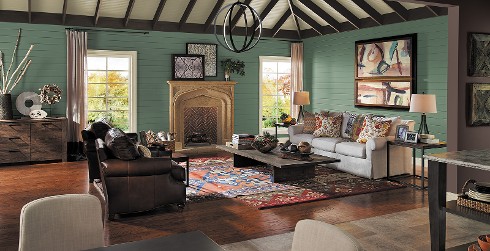 Open concept living room with muted green on walls, off white couch, dark brown leather chairs and dark wood coffee table