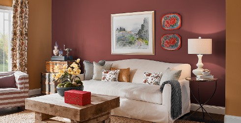 Country styled living room with bronze on main walls, magenta on accent wall, white couch and wood coffee table
