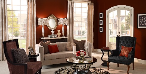Formal living room with deep red on walls, white on trim, light tan tufted couch, and black round coffee table