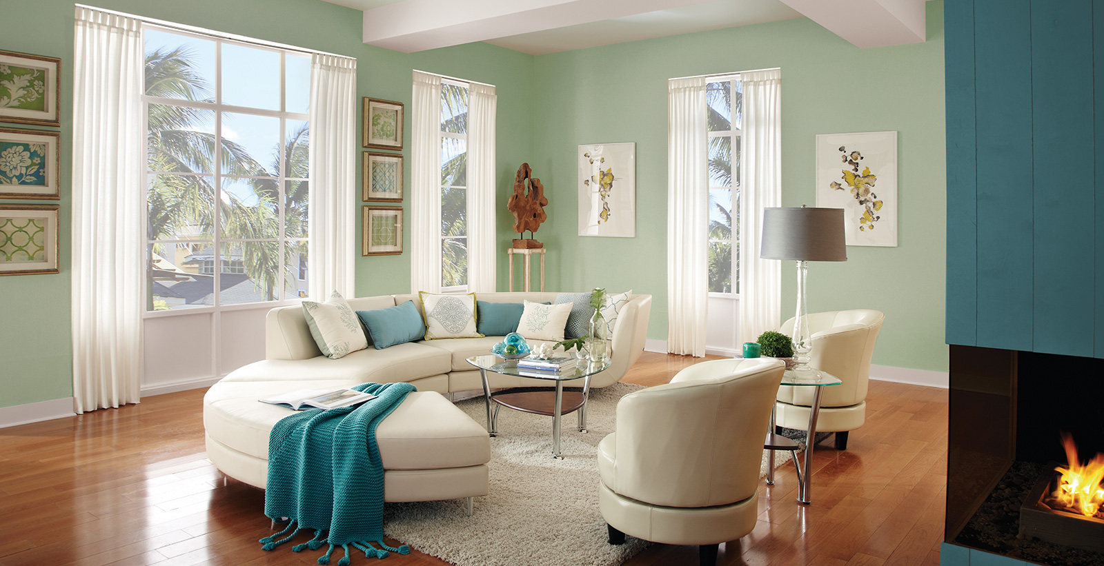 Coastal living room with pale green on main walls, teal on wall with fireplace, white on trim, and cream couch and chairs