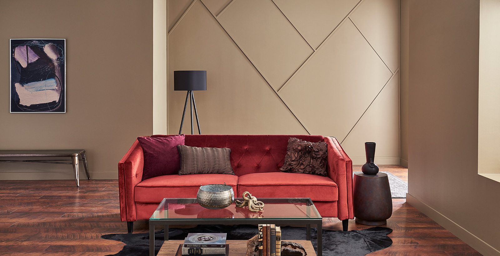 Monochromatic living room with taupe on walls, red tufted couch, glass coffee table, and dark wood flooring