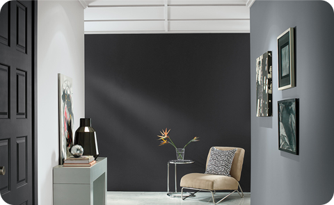 Gray room with dark wall, chair, frames on the wall.