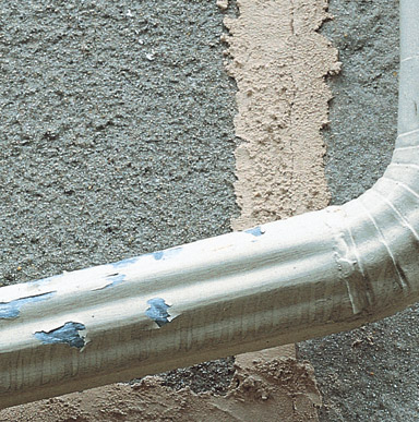 Close up image of a galvanized metal pipe where the paint film is peeling.