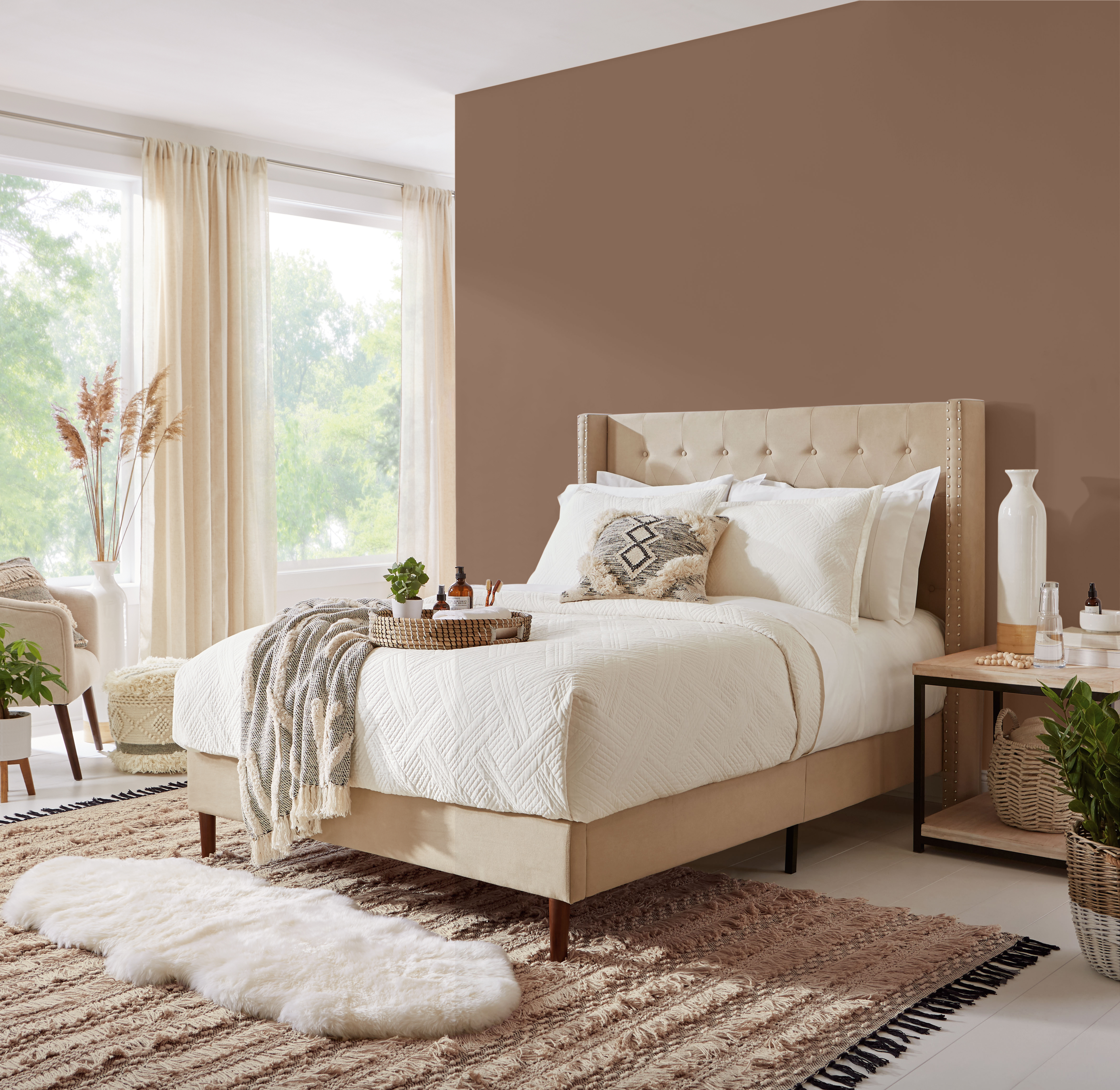 Une chambre contemporaine/boho avec de grandes fenêtres. On y retrouve un lit confortable avec une literie blanche toute simple. Le mur est peint en un brun foncé appelé Mustang sauvage.