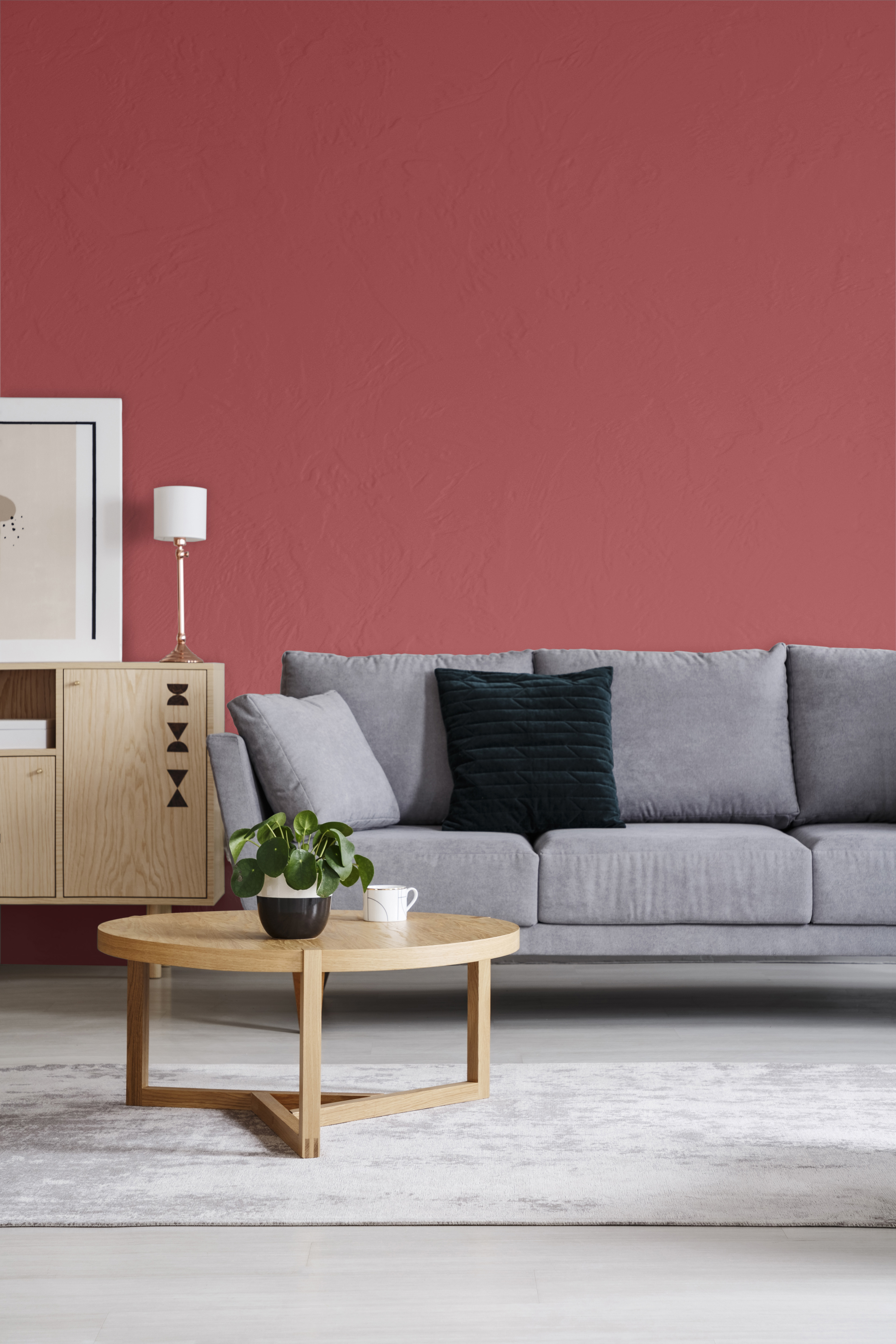 Un mur rouge dans un intérieur de salon élégant avec un canapé et une table ronde. La couleur utilisée sur le mur s'appelle Punch aux airelles.