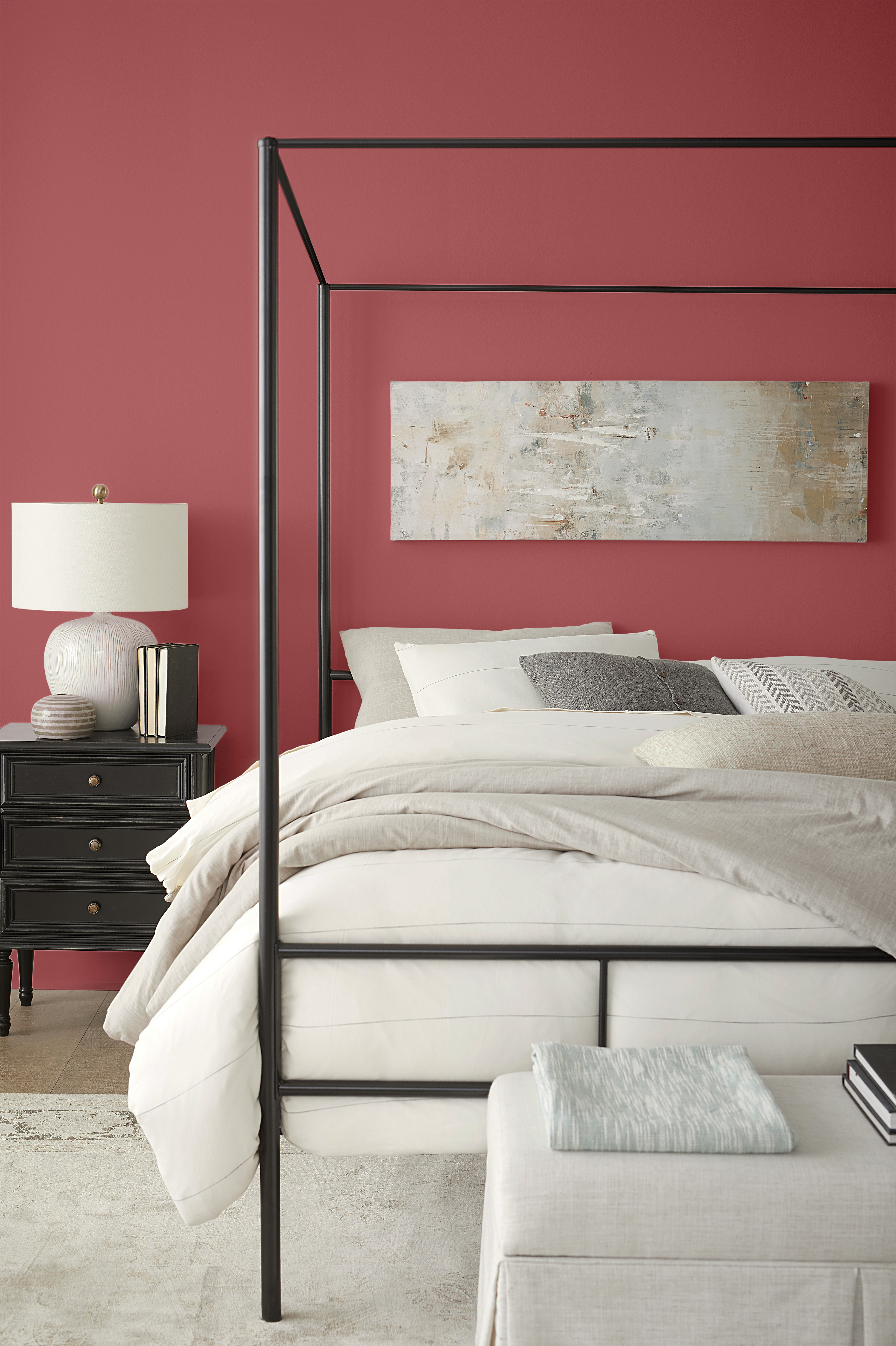 Une chambre contemporaine avec des meubles noirs et des murs rouges. La literie est blanche et beige clair avec des tons neutres de gris. Les murs sont peinturés d'une couleur rouge appelée Punch aux airelles.