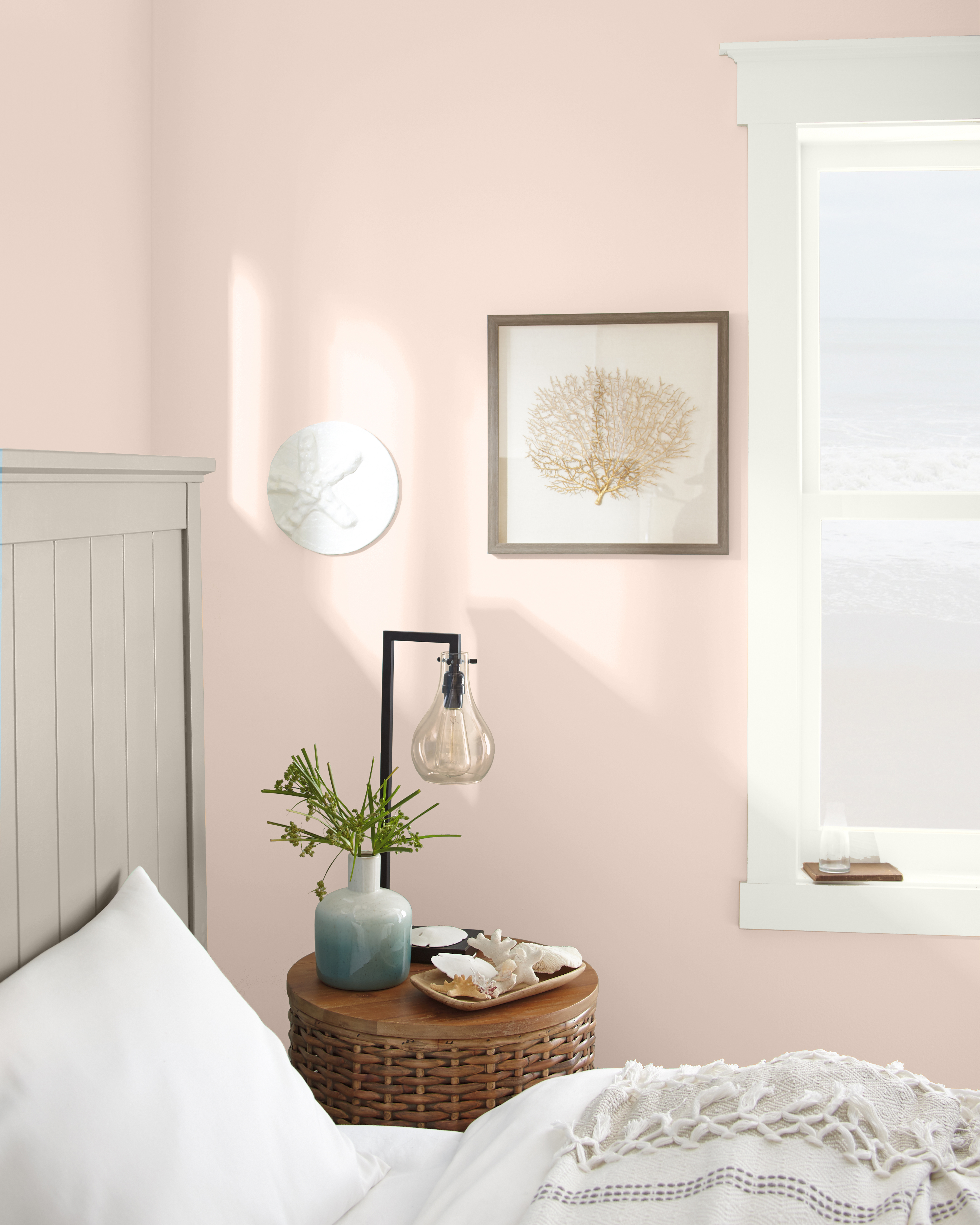 Une chambre d'inspiration bord de mer avec des murs en rose clair. Des tons neutres sont utilisés dans toute la chambre.