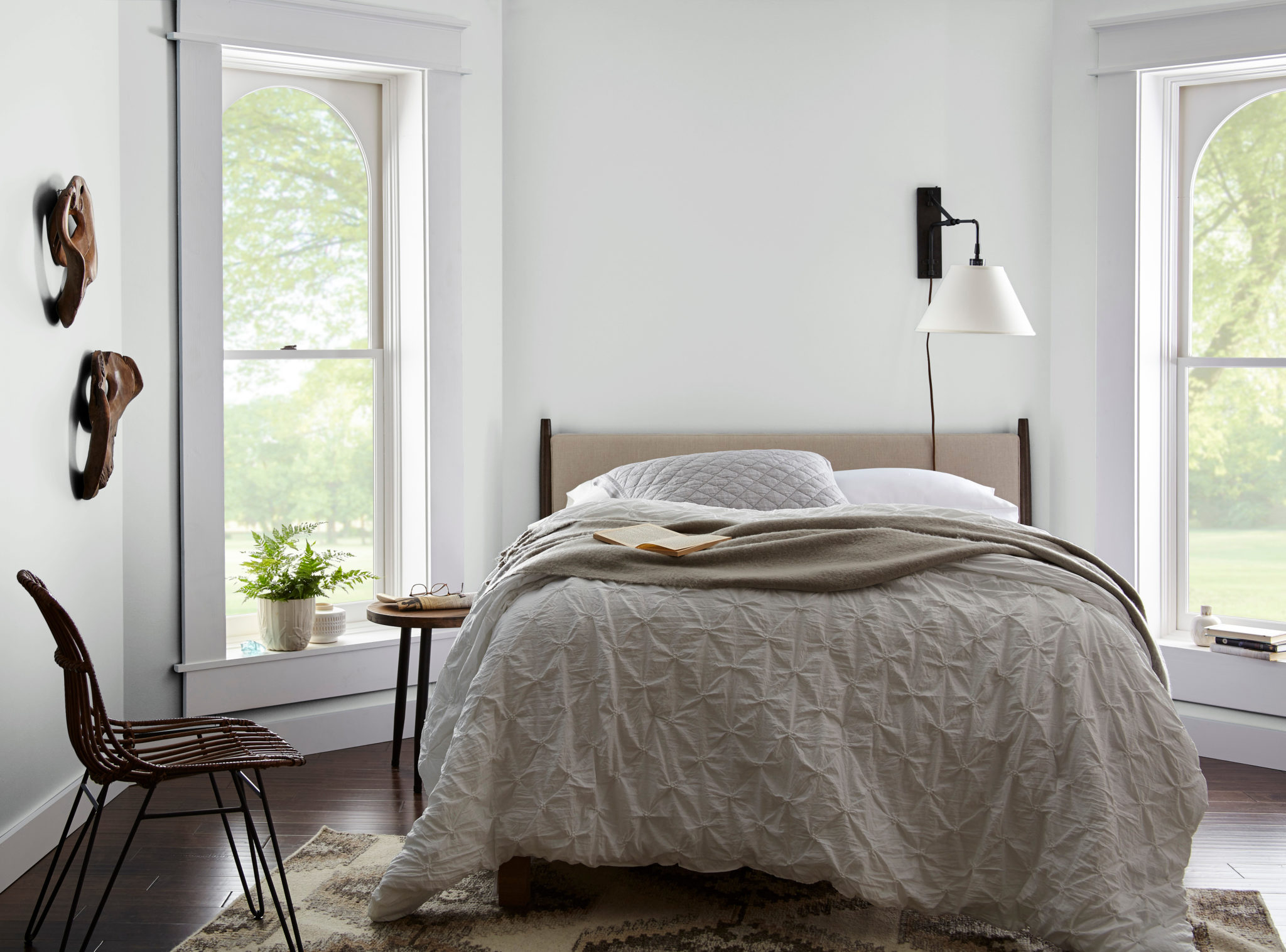 Une chambre décontractée et éclectique avec des meubles simples et des éléments décoratifs en bois, la couleur présentée sur les murs est un blanc froid appelé Givre.
