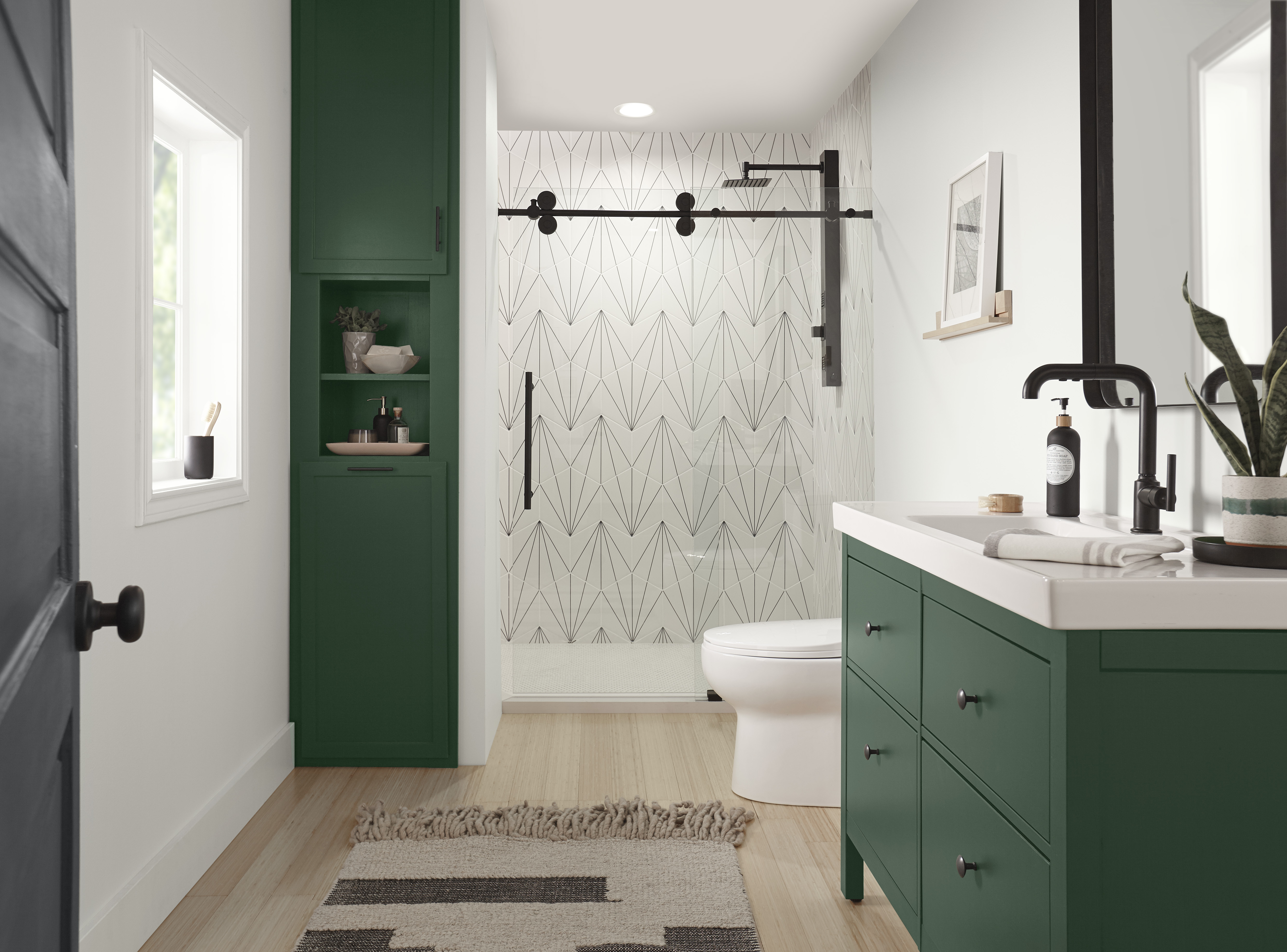 Une salle de bain moderne avec des armoires peintes dans un vert profond et des ferrures noires mates. 