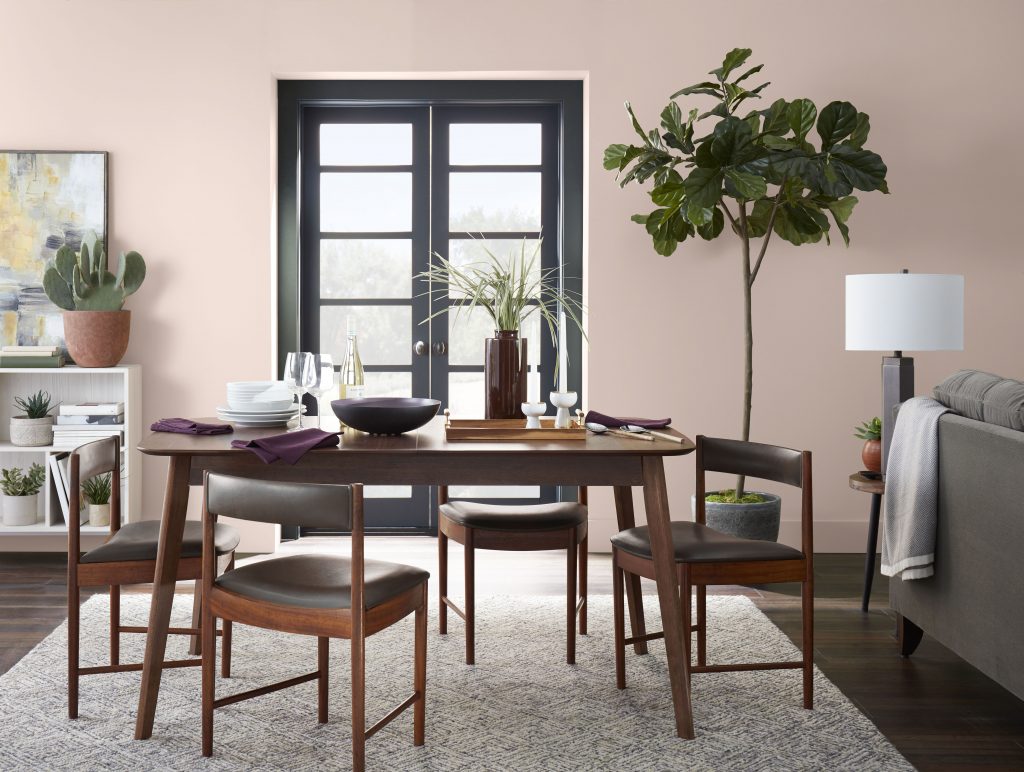 Une salle à manger dont les murs sont peints dans une douce couleur rose et décorée avec des meubles des années 50
