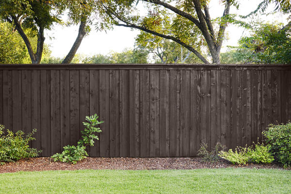 Une clôture en Brun Cordovan avec du gazon et des plantes au premier plan