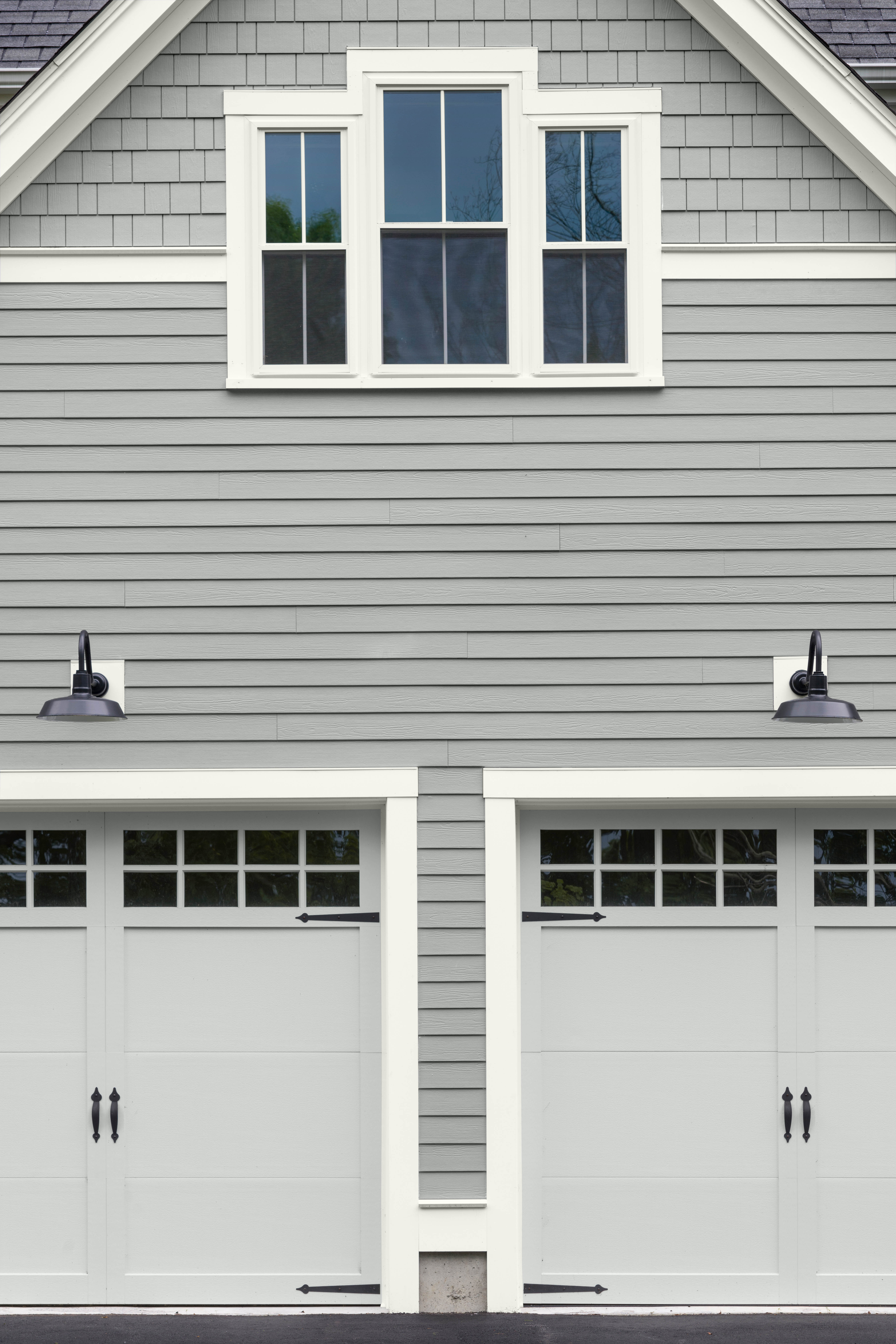 L'extérieur d'une maison avec des bardages dans la couleur Surface lunaire et des portes de garage dans la couleur Platine