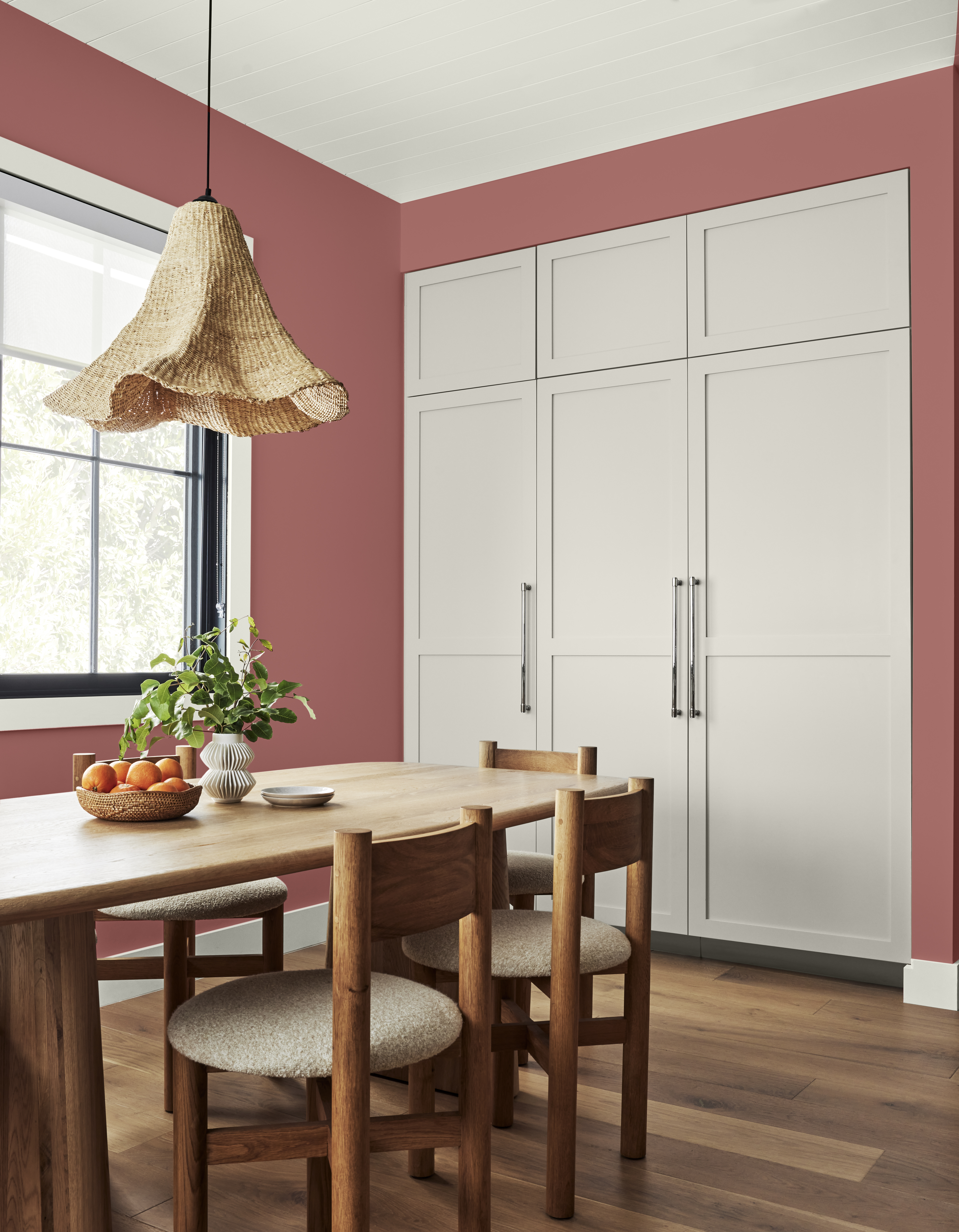 Une salle à manger avec des murs dans la couleur Vermillon et une grande armoire de rangement dans la couleur Perspective grise