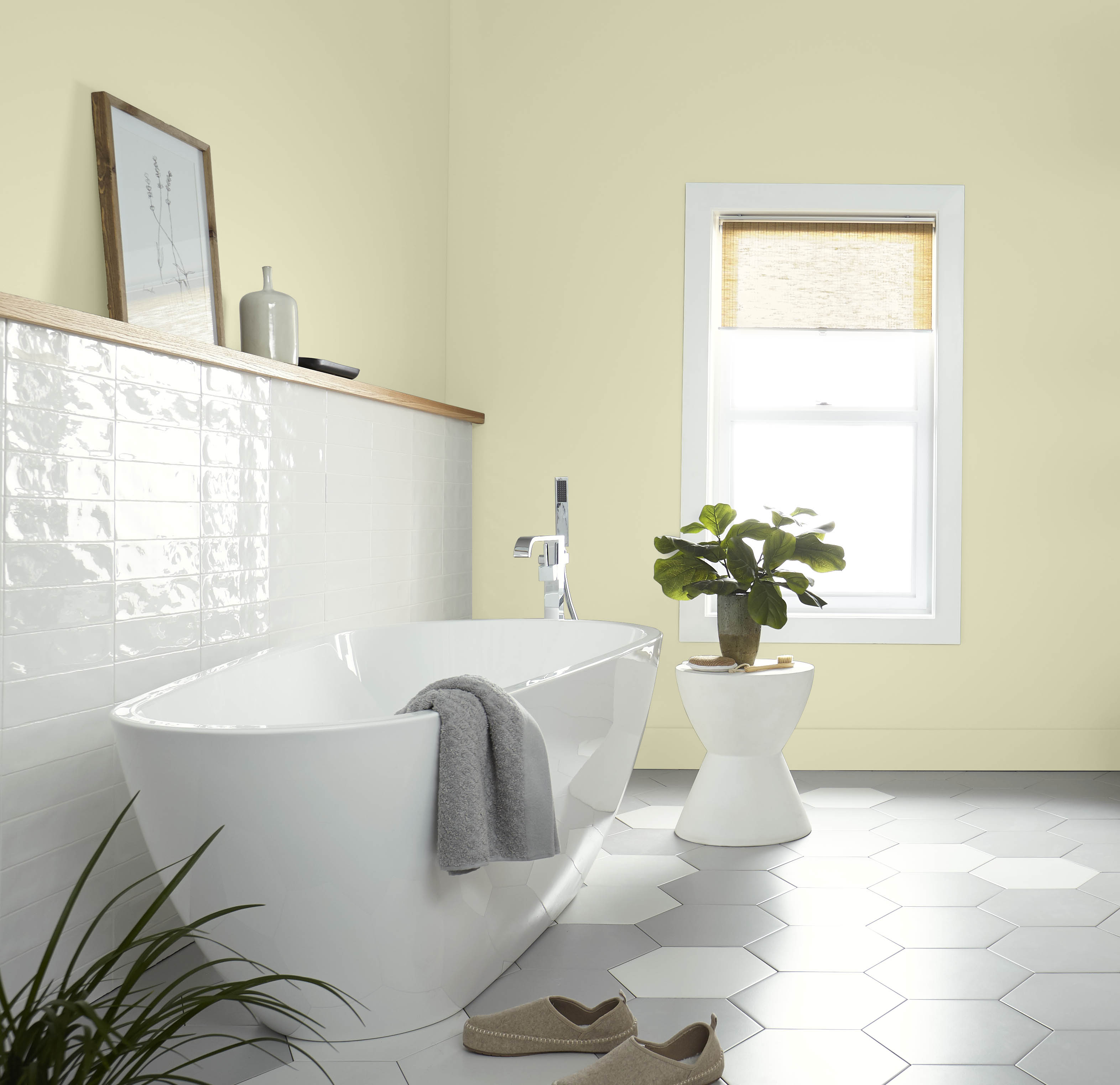 Une salle de bain lumineuse aux murs et plinthes dans la couleur Hybride, avec baignoire et petite table 