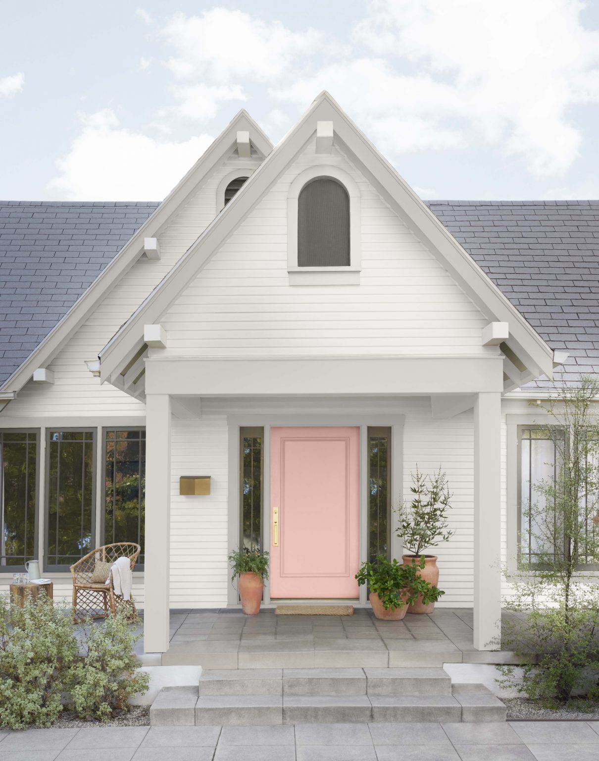 L'extérieur d'une maison blanche avec la porte d'entrée peinte dans la couleur Rose prairie