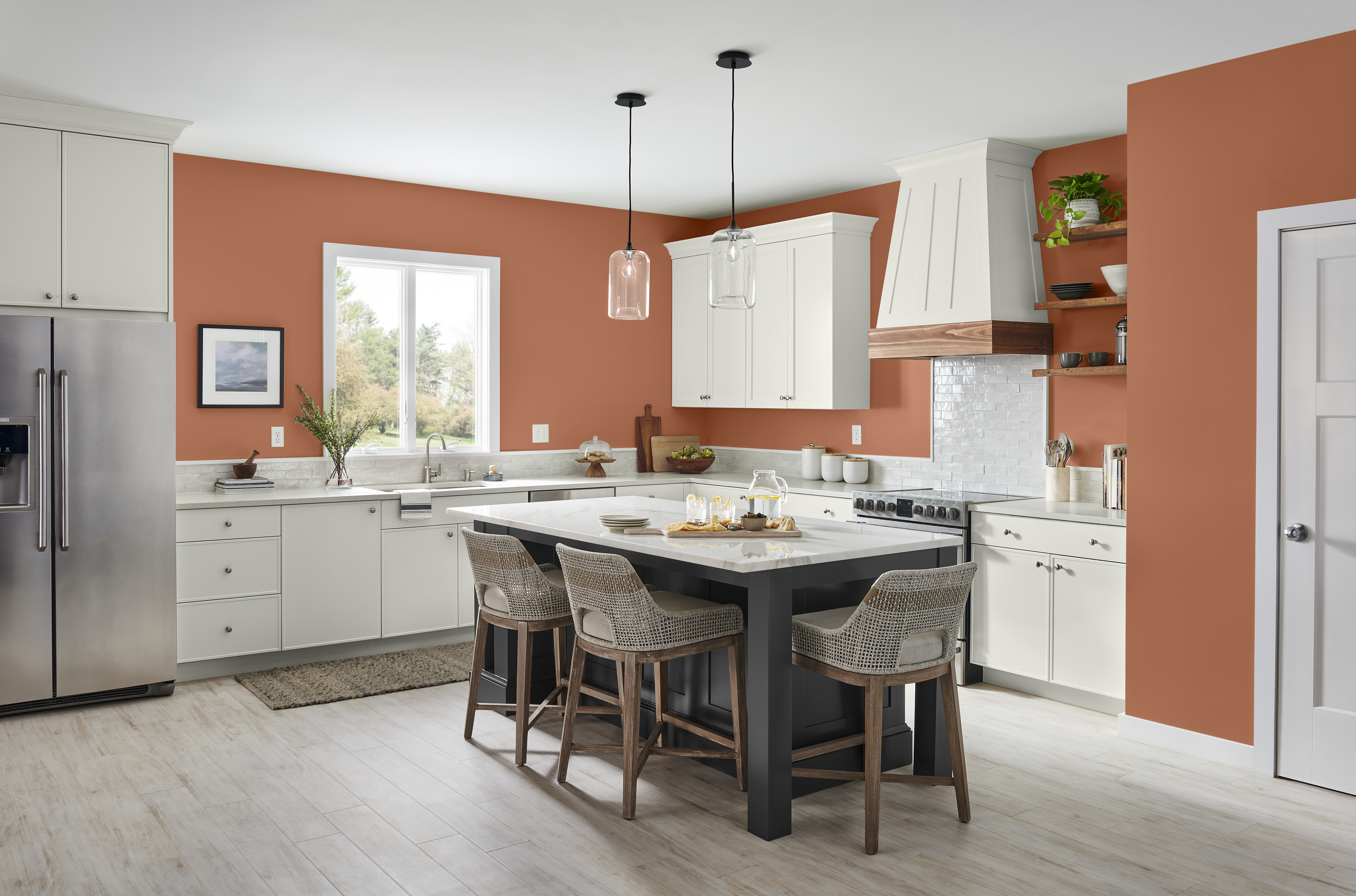 Une grande cuisine avec des murs de couleur Flambé à l’orange, des armoires blanches et un îlot noir