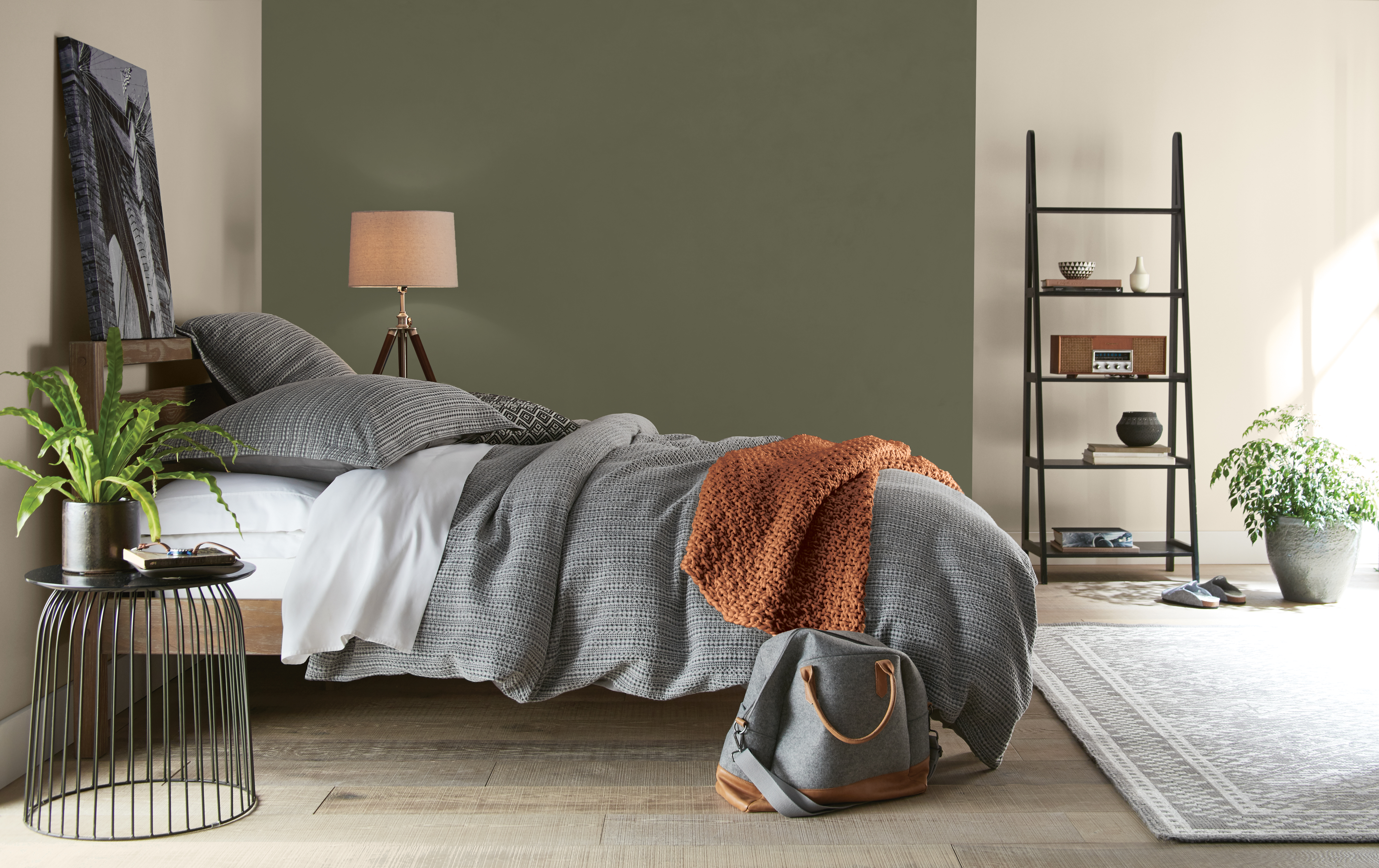 Une chambre à coucher avec des murs dans la couleur Encore plus beige et un mur d'accent dans la couleur Olivier de montagne à côté du lit