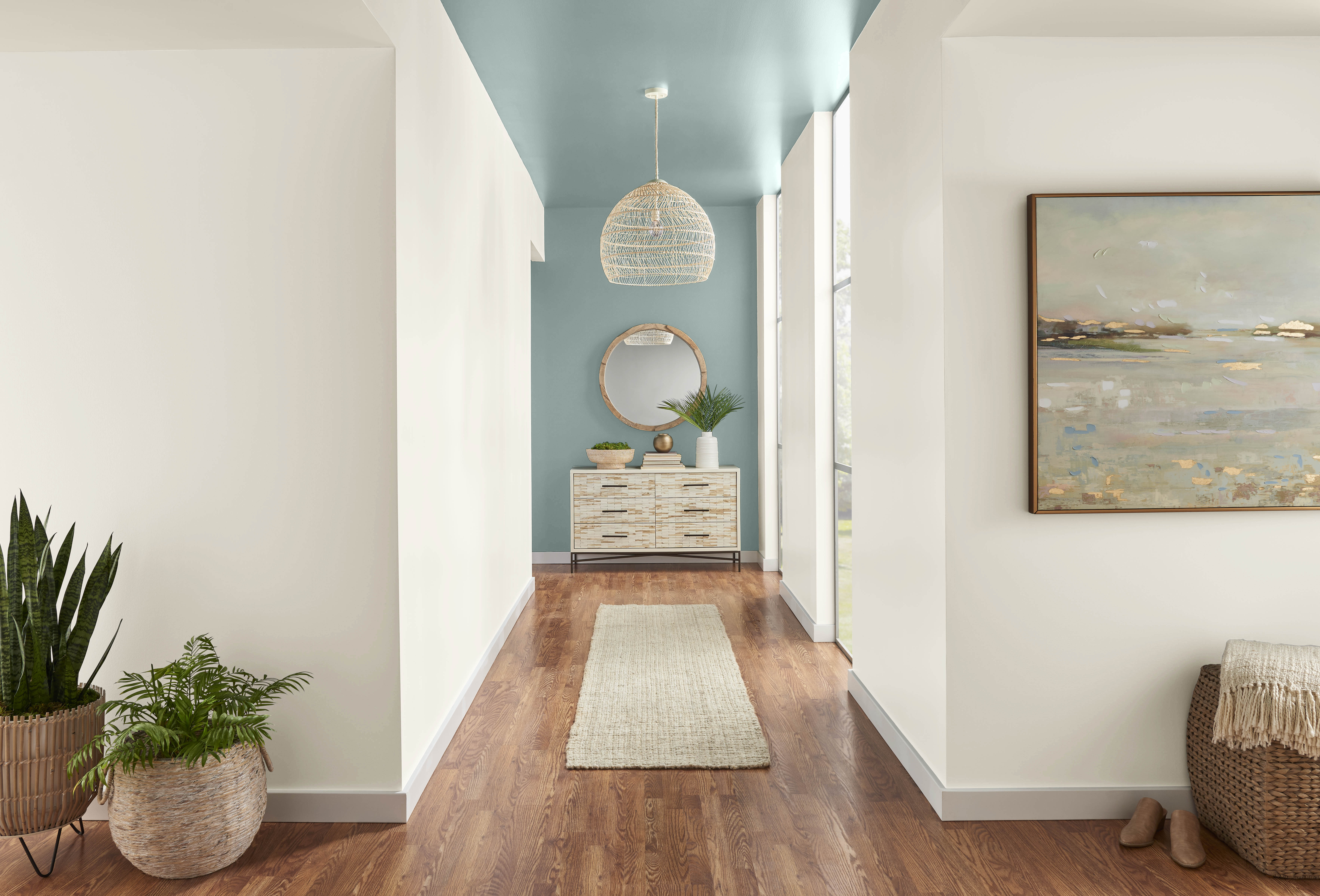 Un long couloir aux murs blancs avec un mur d'accent et plafond peints dans une couleur bleu-vert poudreux