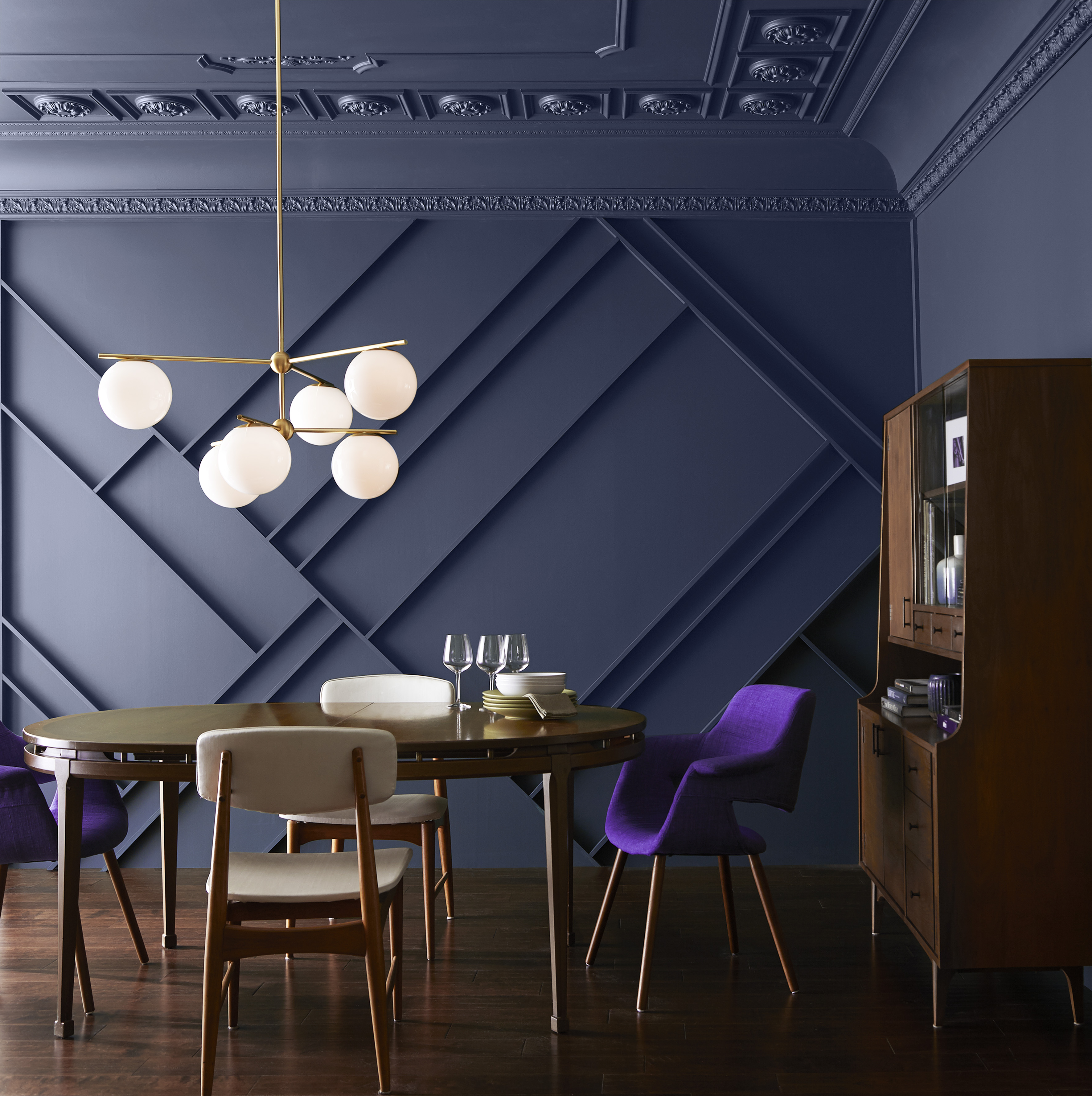 Une salle à manger audacieuse avec des murs et plafond peints dans une couleur marine foncée, décorée d'une table, chaises et buffet en bois