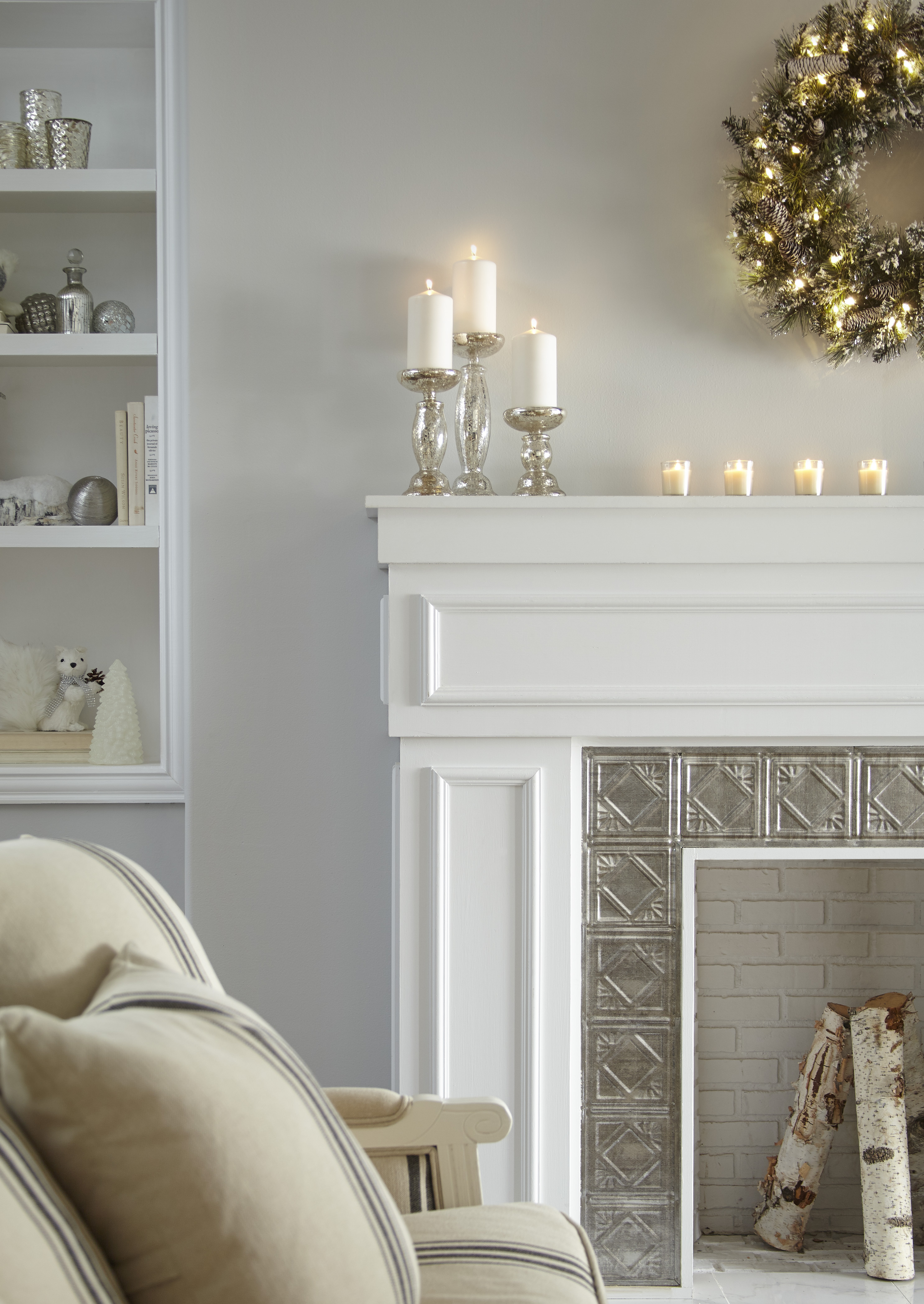 Un salon blanc avec un foyer blanc décoré d'une couronne de Noël et de bougies 