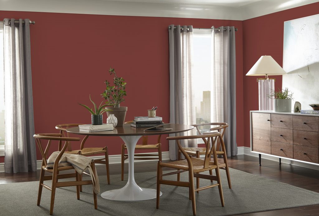 Une salle à manger aux murs peints d'un rouge audacieux décorée d'une table, chaises et buffet d’inspiration années 50
