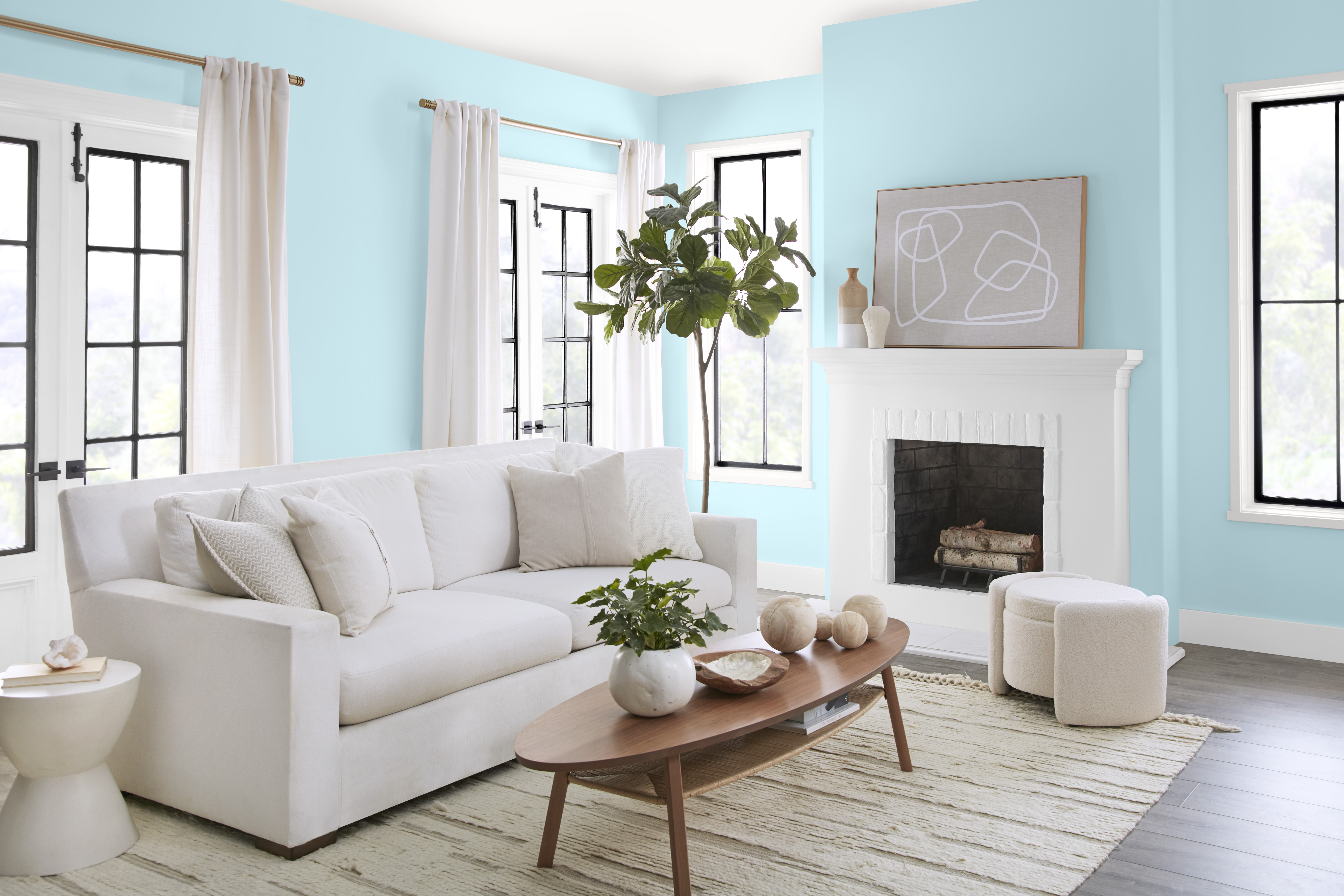 Un salon lumineux aux murs peints en bleu clair, agrémenté d'un mobilier et décor blancs et neutres