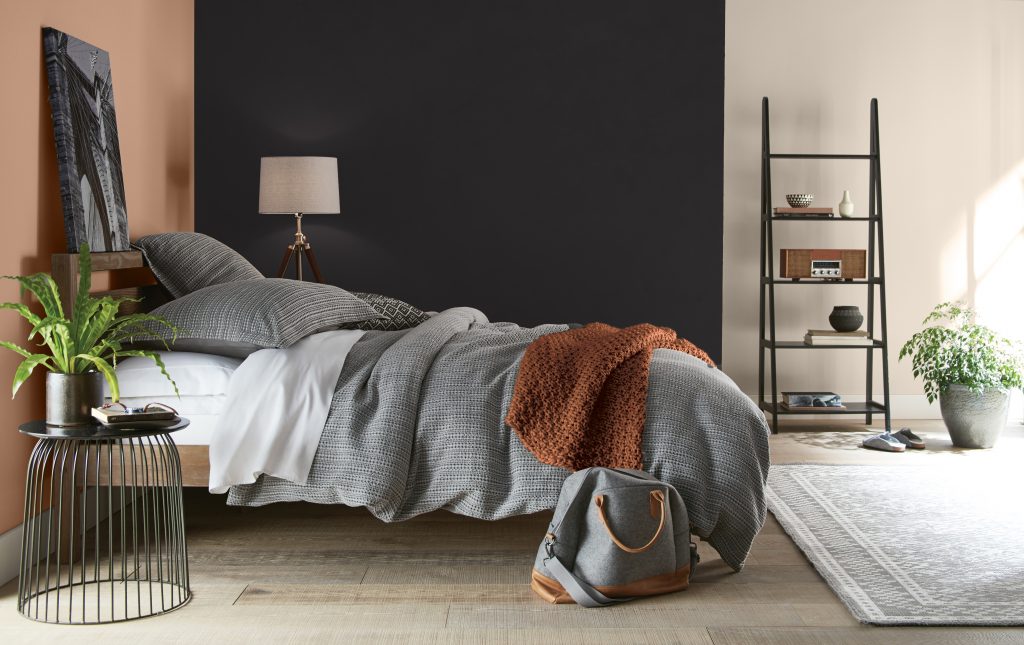 Une chambre à coucher dont les murs sont peints en différentes couleurs - un ton de terre cuite, du noir et une couleur neutre claire