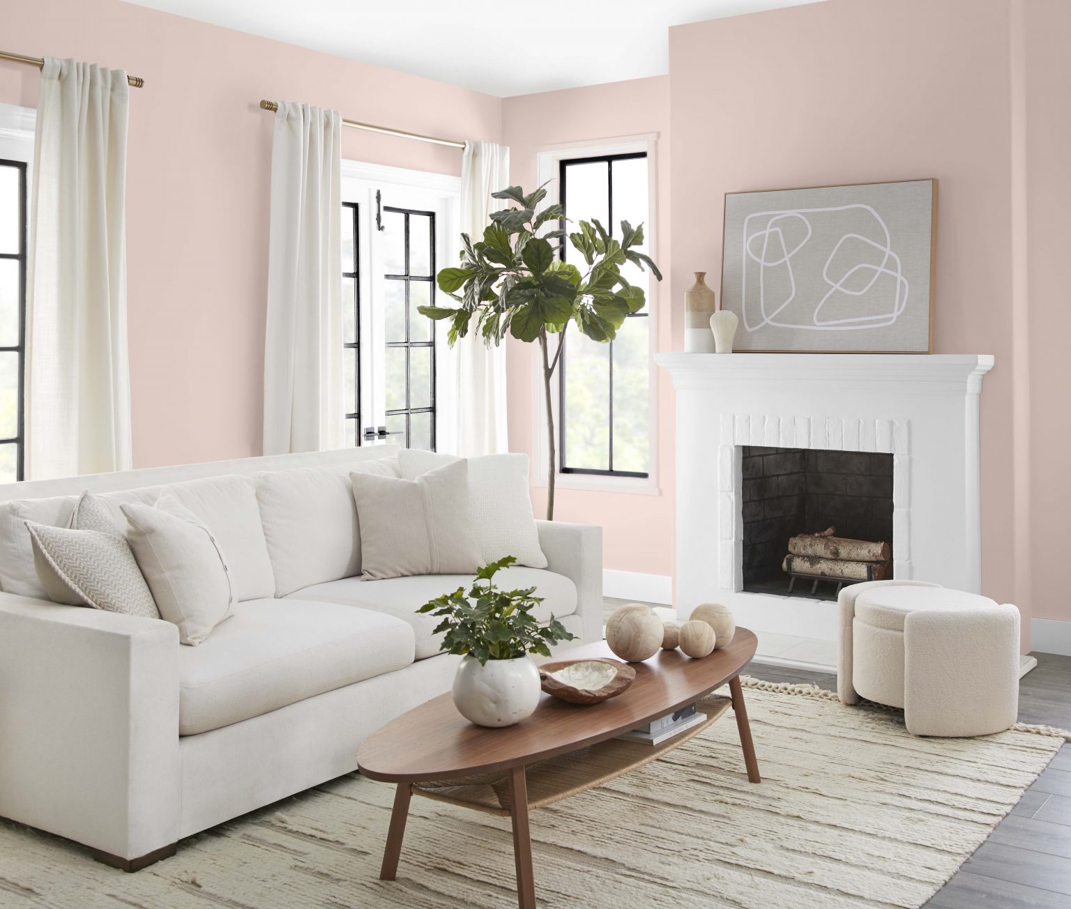 Un salon décontracté dont les murs sont peints dans une couleur neutre rose pâle, avec un foyer blanc, des garnitures de fenêtres noires et blanches et des meubles neutres
