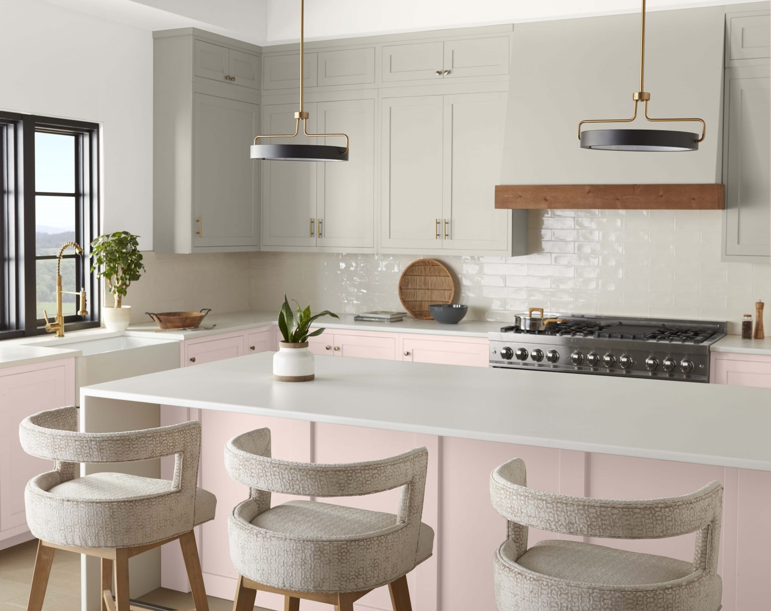 Une cuisine contemporaine aux armoires du haut peintes en gris clair et armoires du bas et îlot peints en rose clair neutre