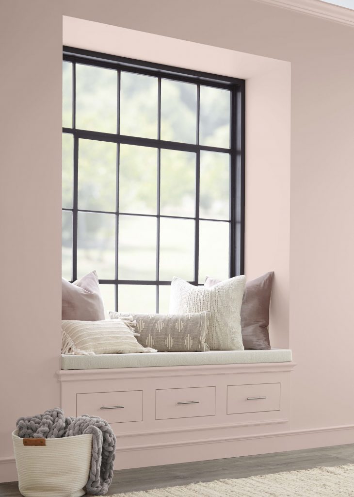 Un coin lecture avec des murs et tiroirs peints dans une couleur neutre rose pâle