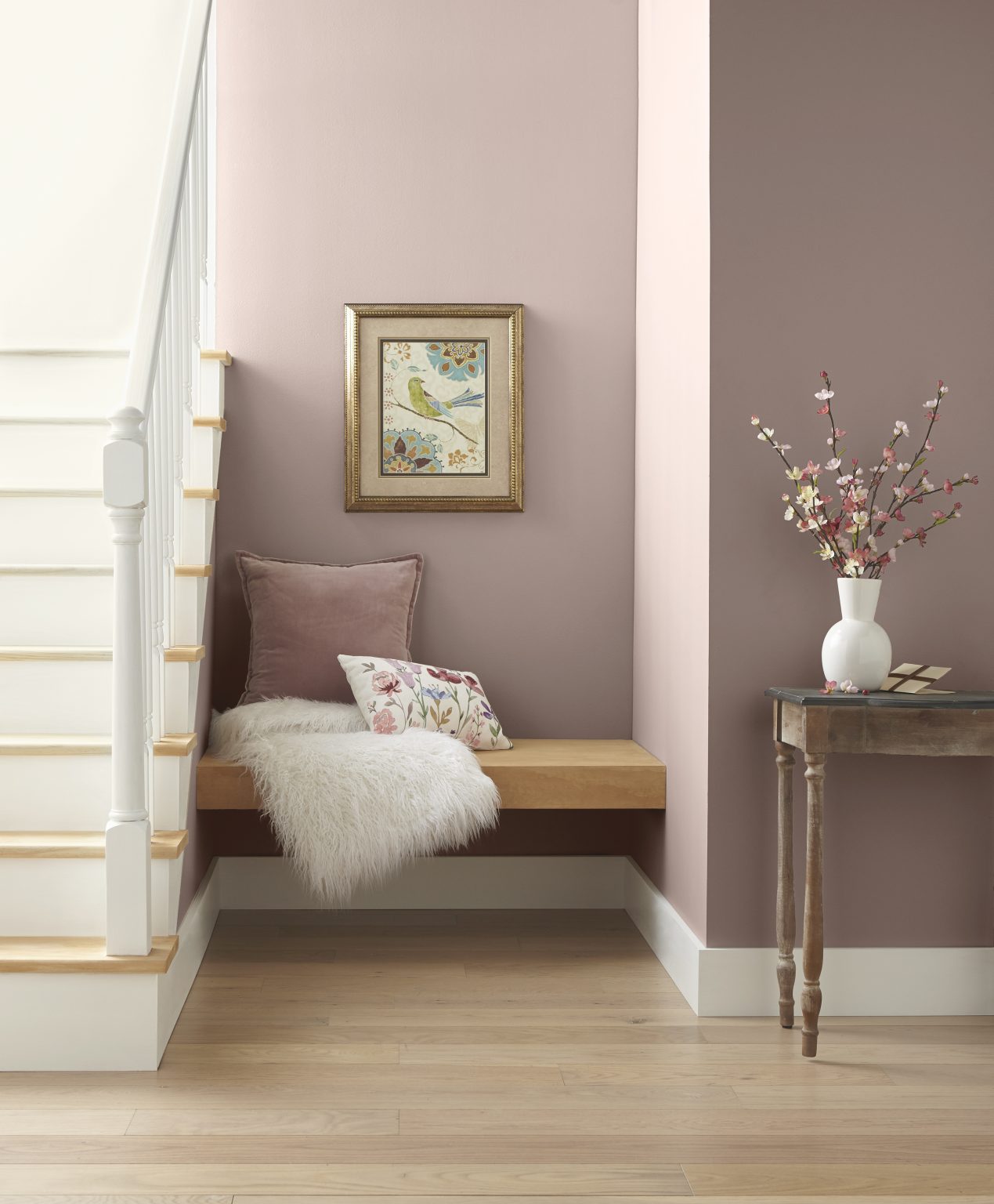 Un petit coin près de l'escalier avec des murs peints dans une couleur de rose poudreux, aménagé avec des meubles et un décor en teintes neutres