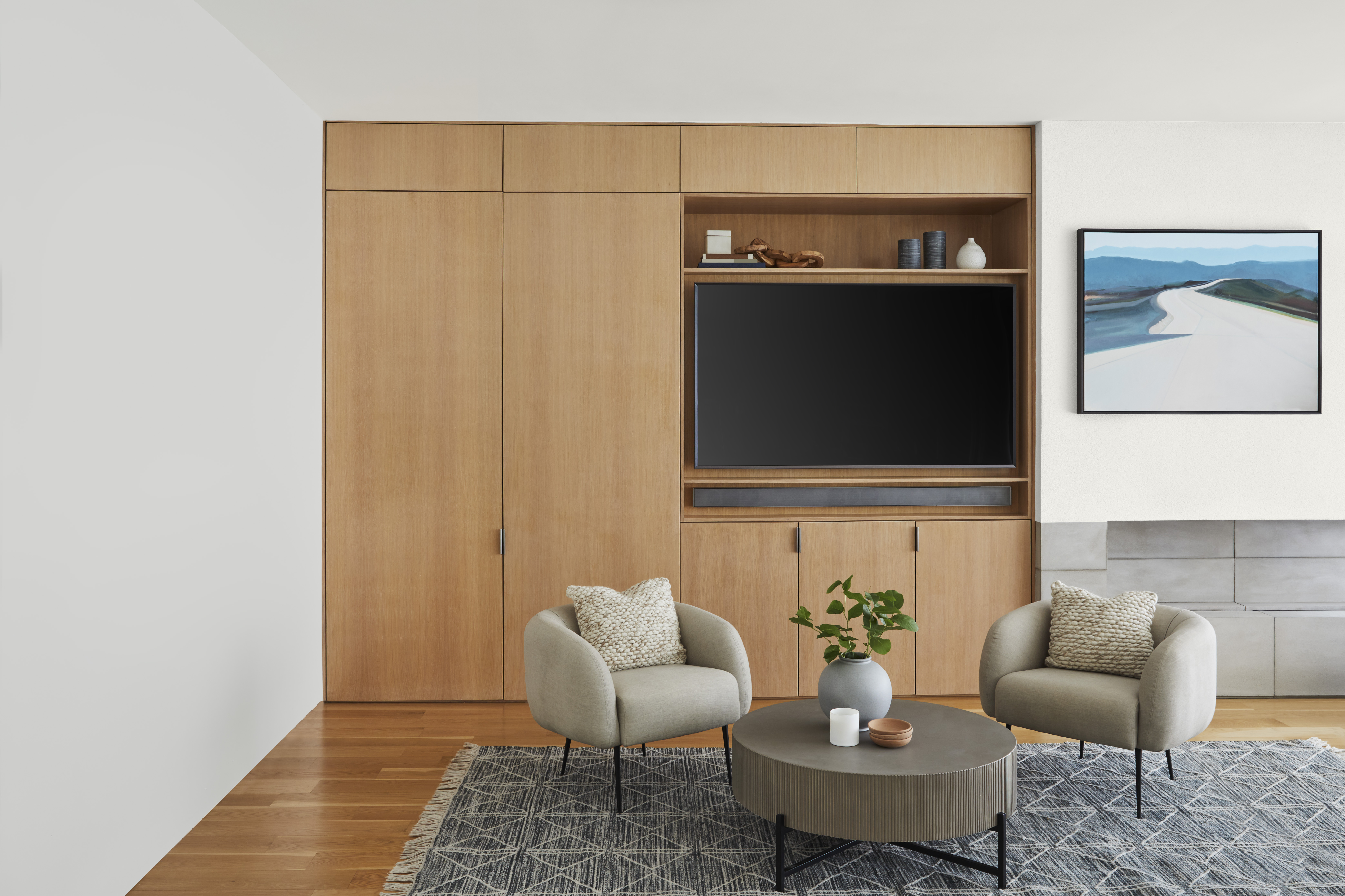 Un salon aux murs blancs avec un meuble multimédia en bois et des armoires encastrées
