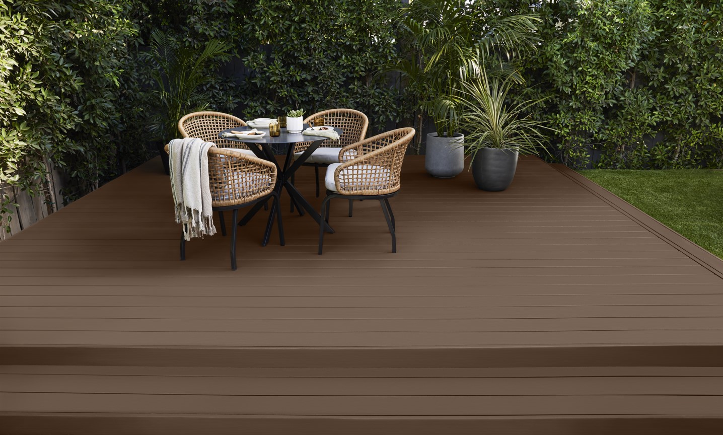 Une terrasse en bois dans un brun opaque avec une table et des chaises d'extérieur
