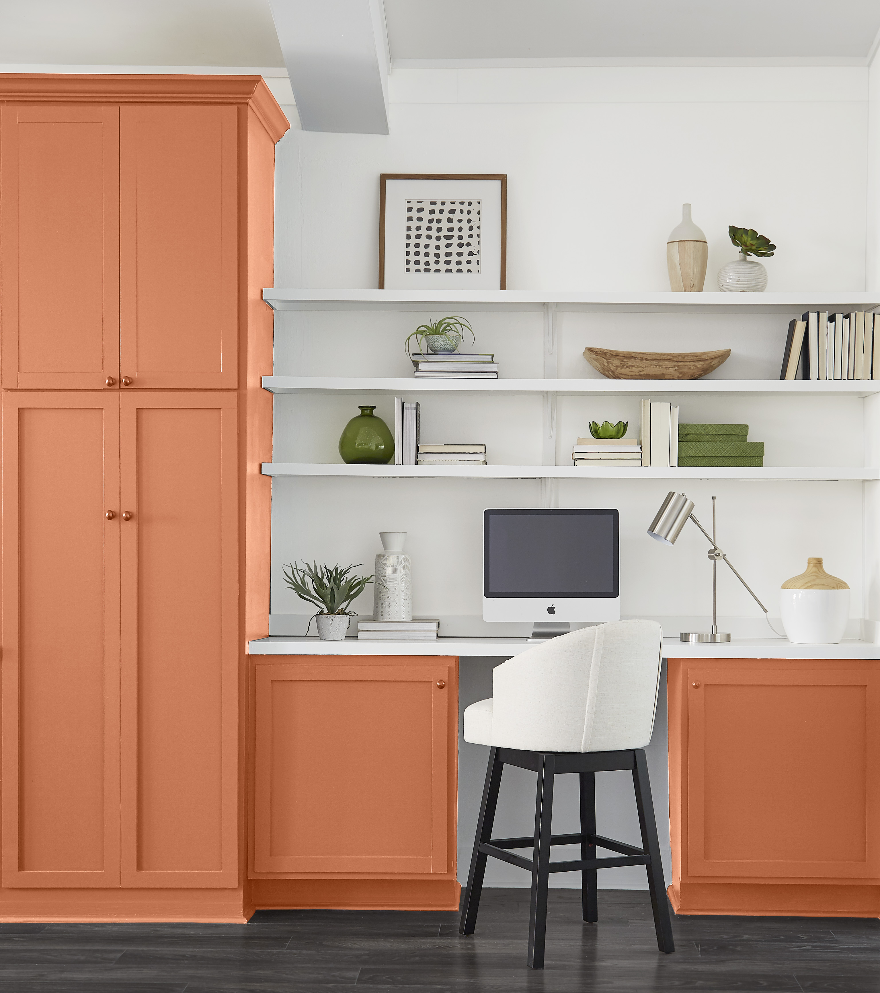Un espace de rangement et de bureau intégré avec des armoires peintes dans une couleur profonde d’orange cuivré