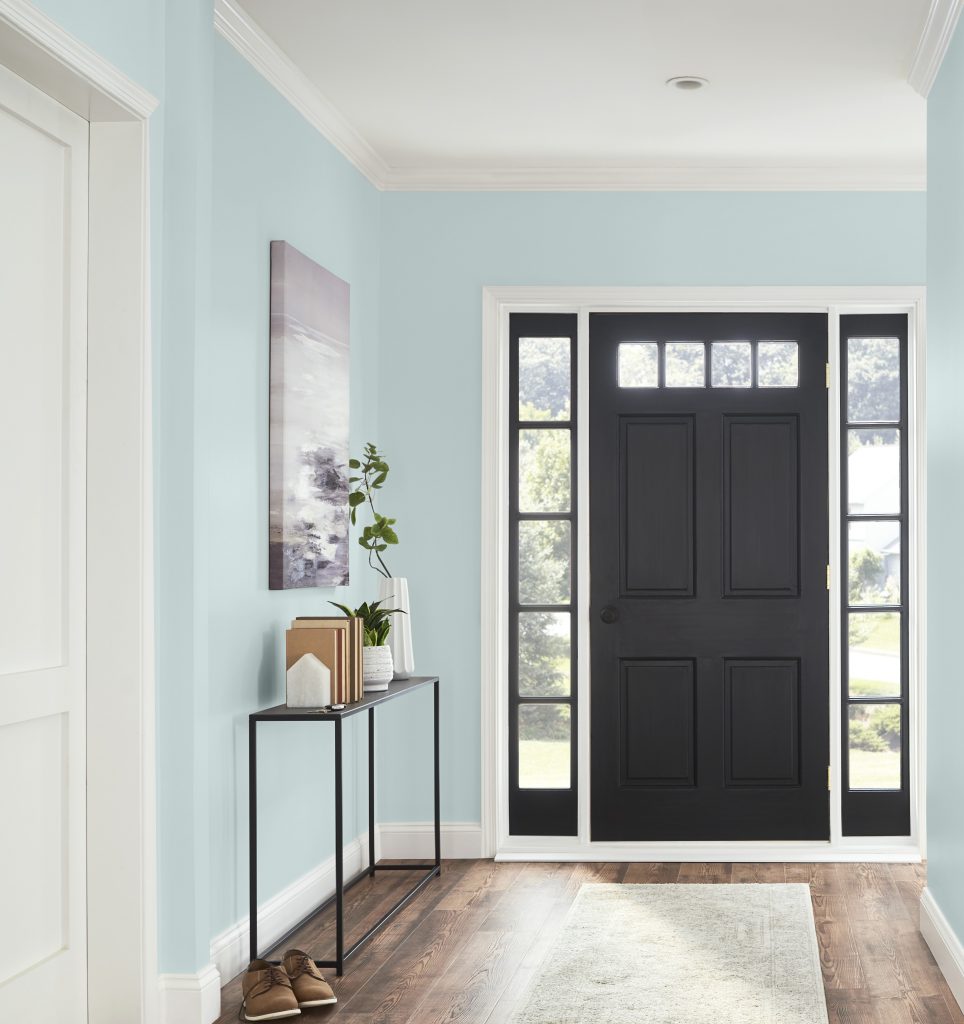 Une entrée avec des murs peints en bleu pâle et une porte en noir contrastant 