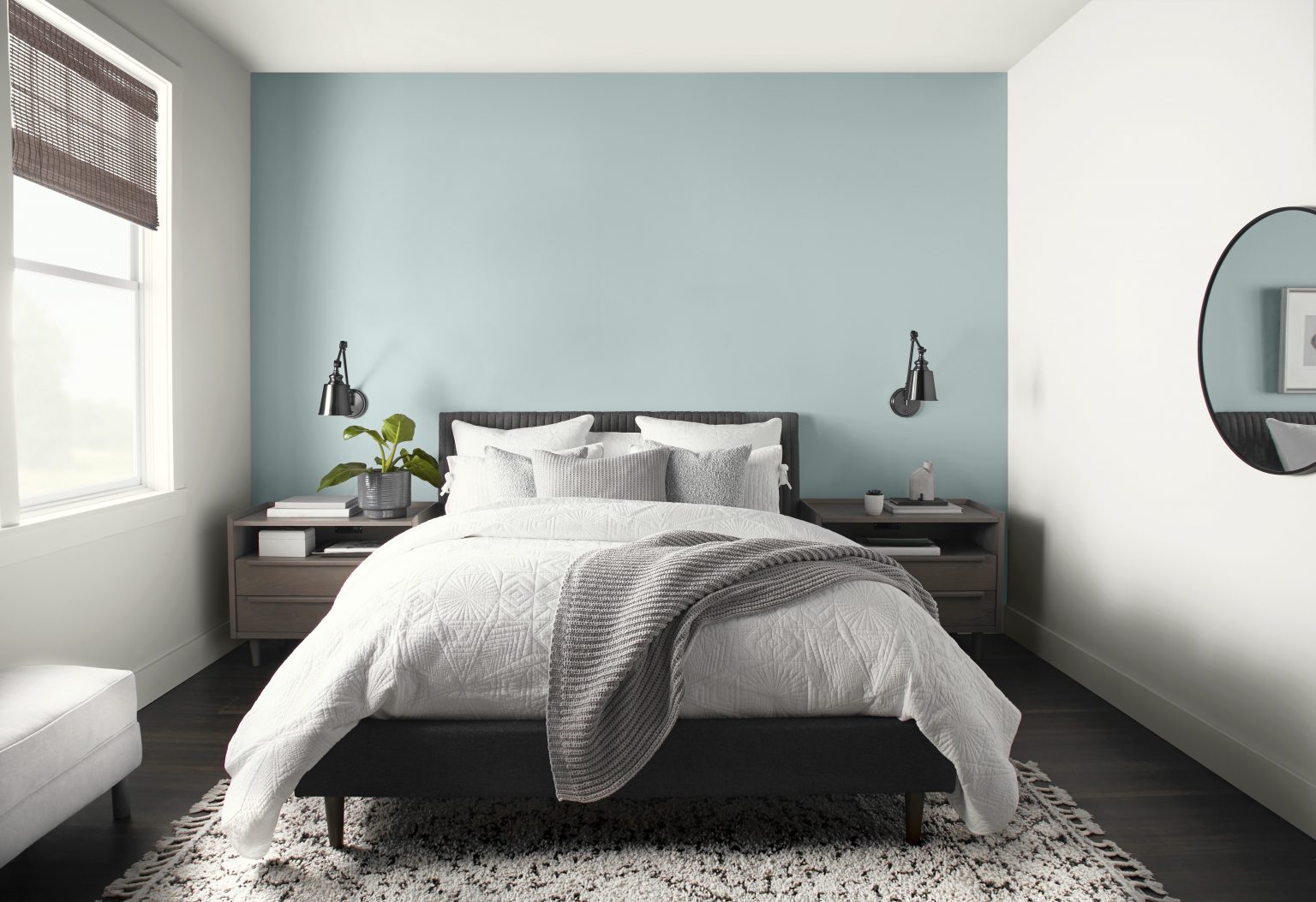 Une chambre d'un blanc éclatant avec le mur de la tête de lit en bleu pâle