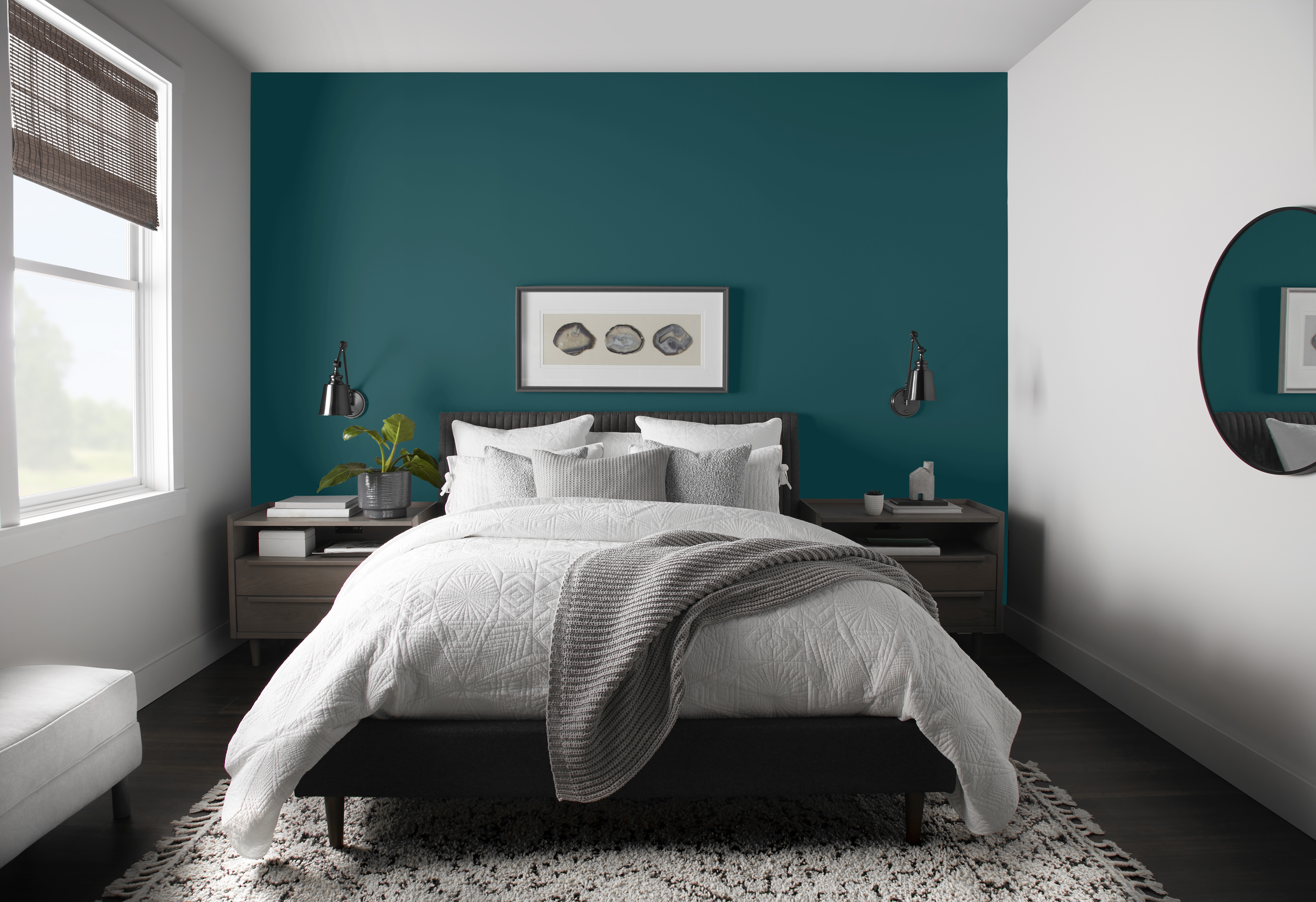 Une chambre blanche dont le mur de la tête de lit est peinturé d’un turquoise profond