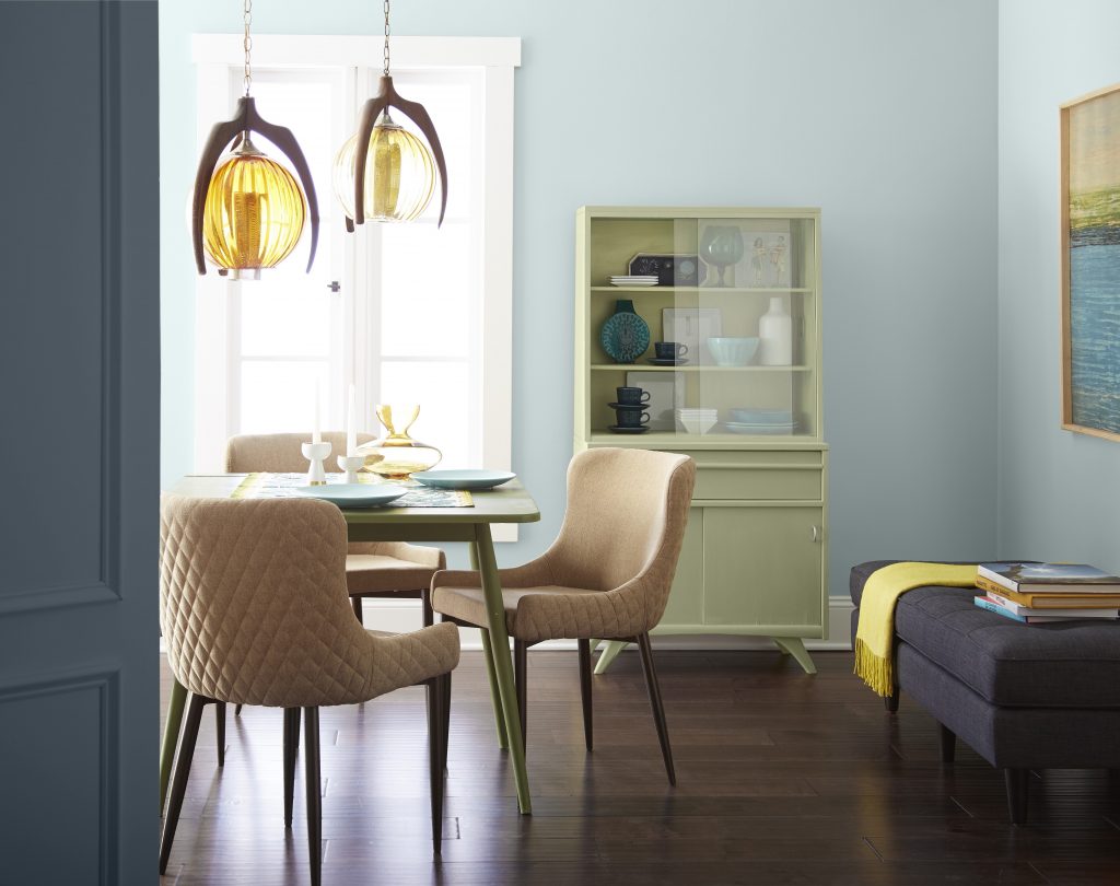 Une salle à manger éclectique avec des murs peints en bleu pâle agrémentée d'un décor et de meubles rétro