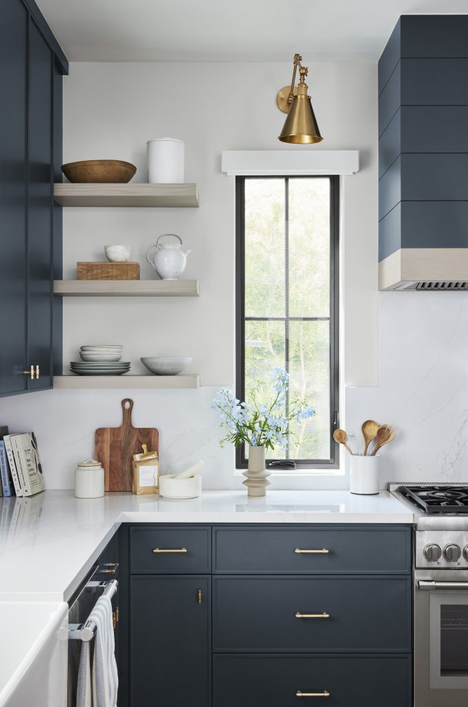 Une cuisine avec des armoires peintes en un bleu profond avec un lustre semi-brillant