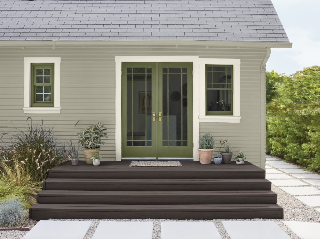 Extérieur d'une petite maison aux bardages gris-vert avec une double porte verte