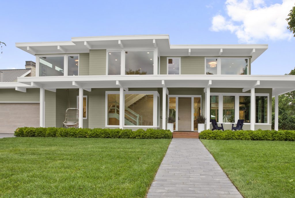 L'extérieur d'une grande maison contemporaine avec des garnitures blanches et une porte d'entrée en bois clair