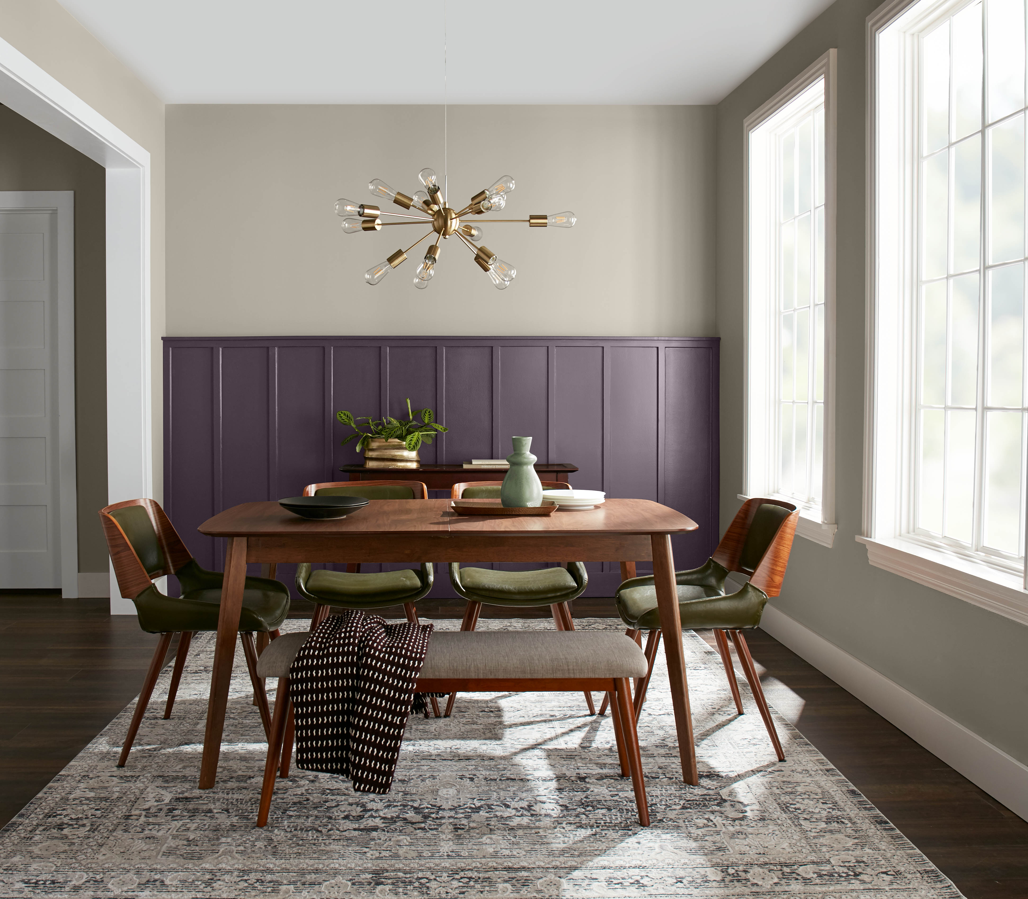 Une salle à manger avec un mur d’accent violet foncé entouré de teintes neutres.