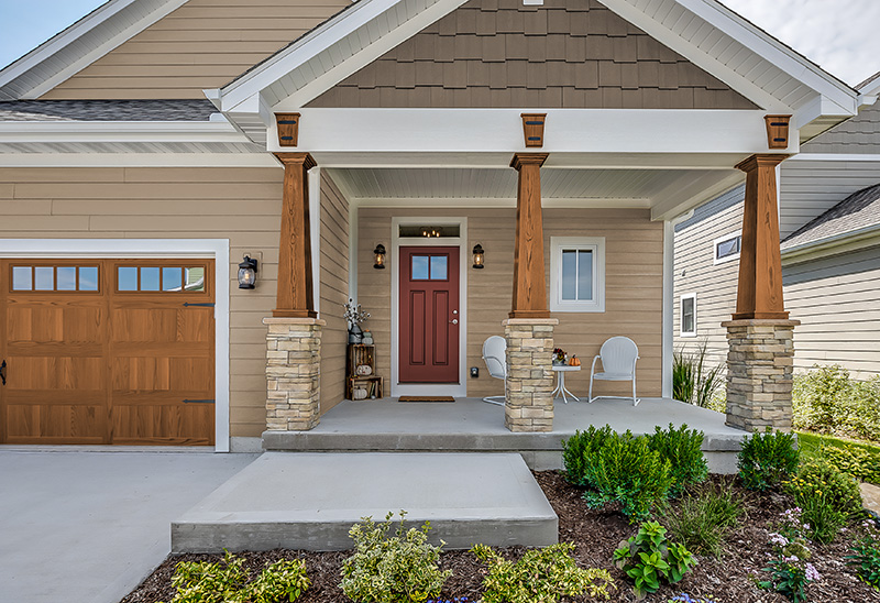 Une maison de style Craftsman avec une palette de peinture à deux tons et une porte d'entrée rouge intense appelé Piment rouge. L'agencement des tons terreux et de la porte vive crée un charme rustique et accueillant.