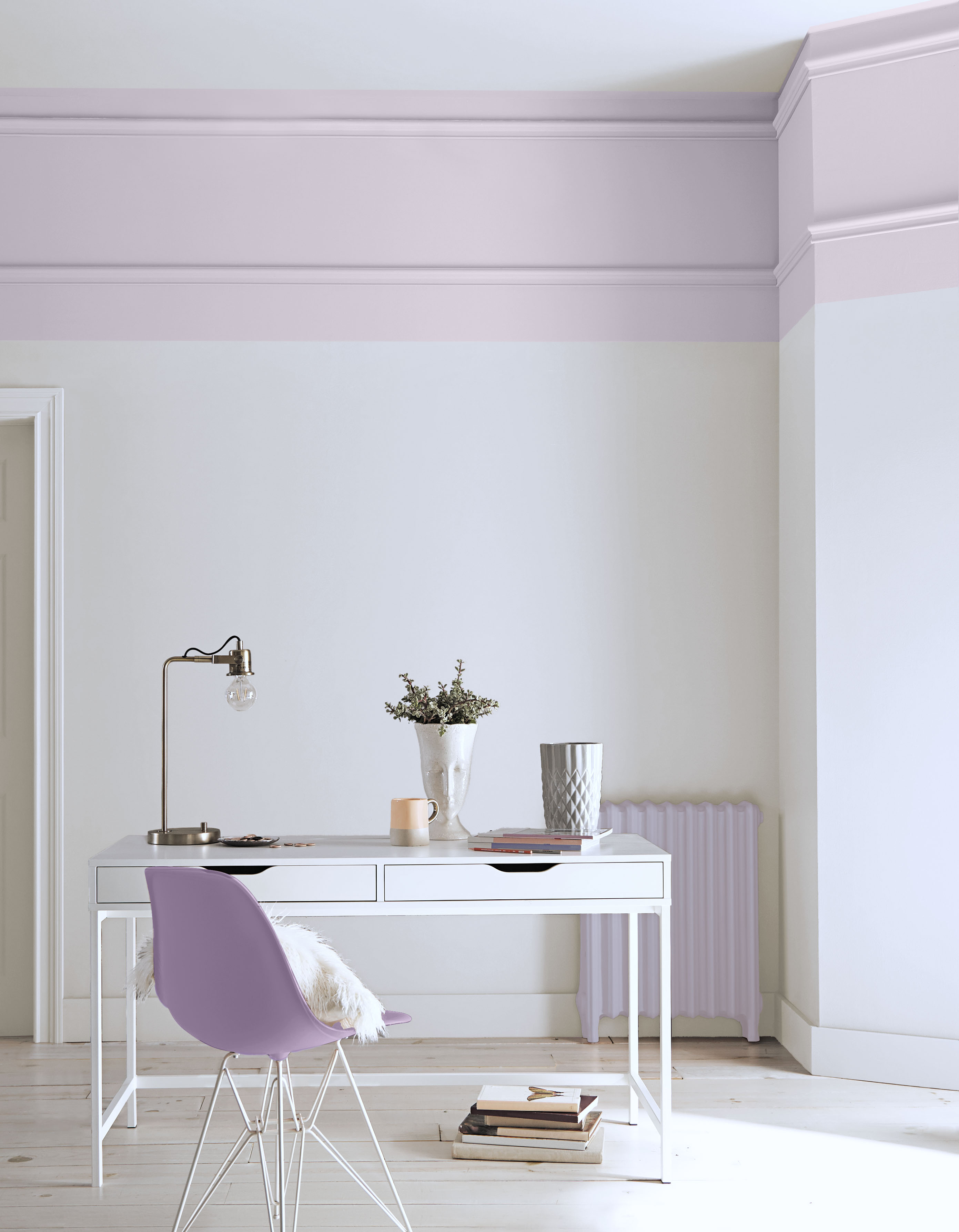Espace de télétravail avec murs blancs ornés d’une bordure rose qui crée une moulure décorative sous le plafond