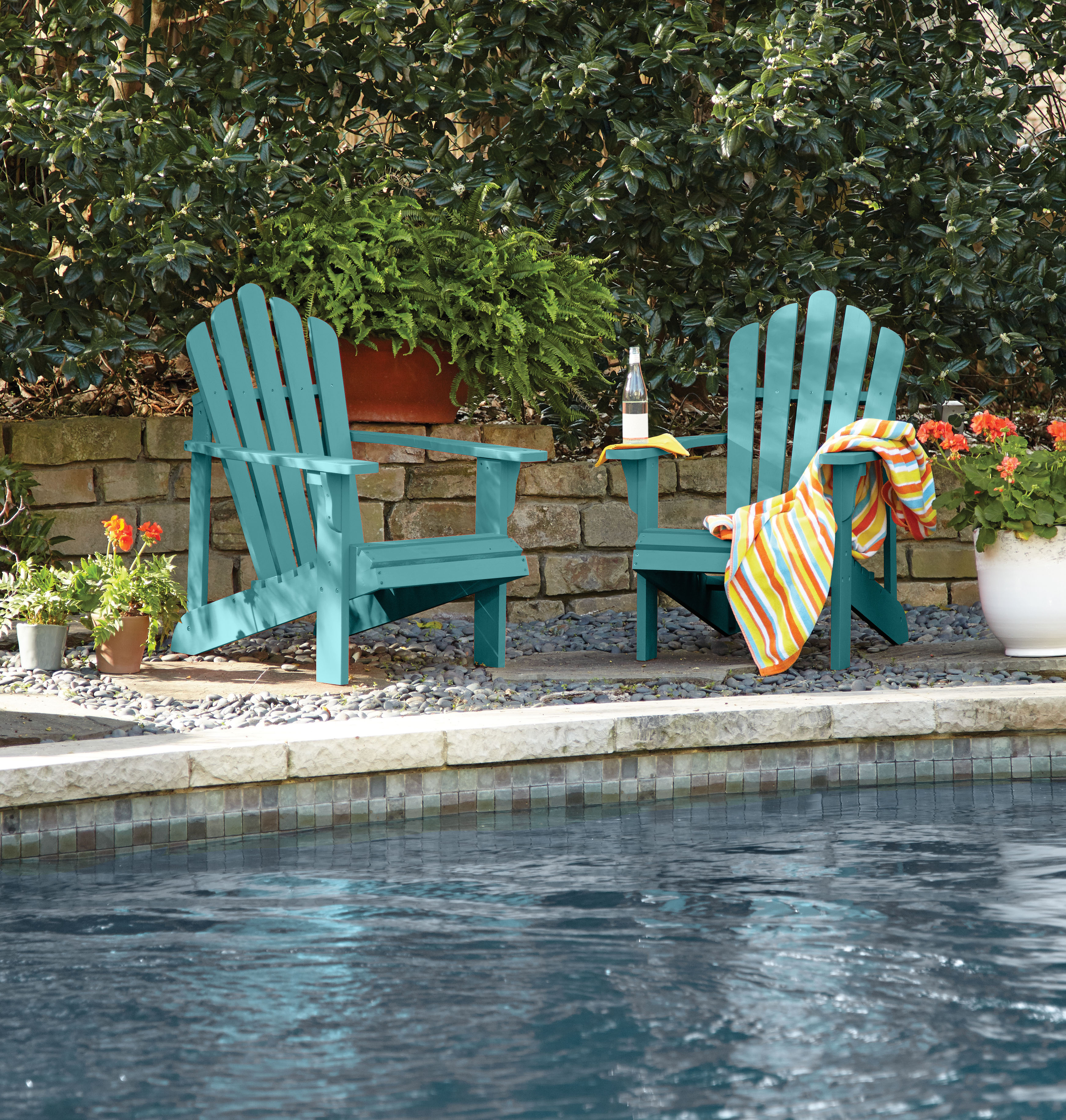Cette image montre des chaises Adirondack peintes d’un bleu-vert vibrant.