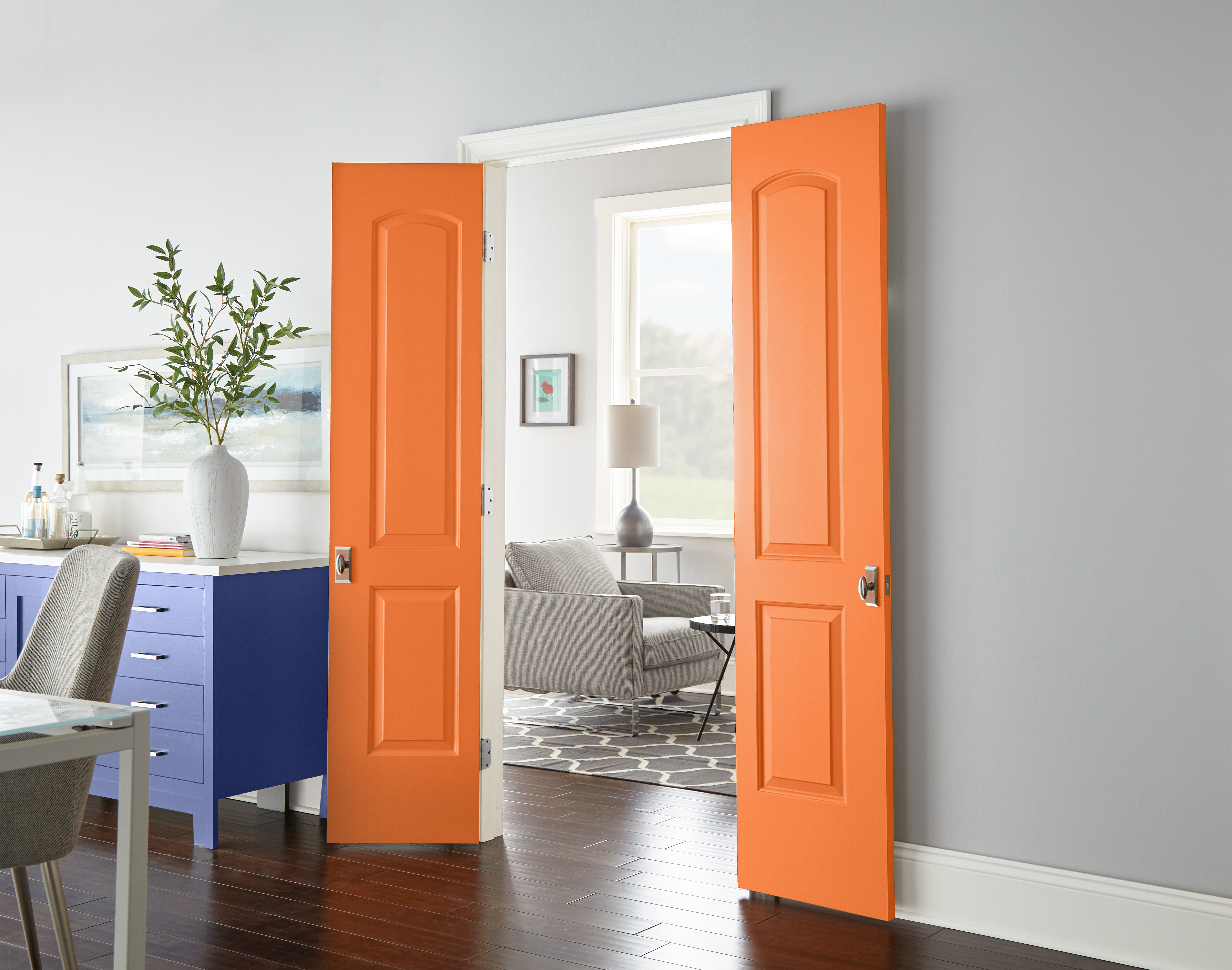 Cette image montre des portes orange vif qui contrastent audacieusement avec les murs peints en gris.