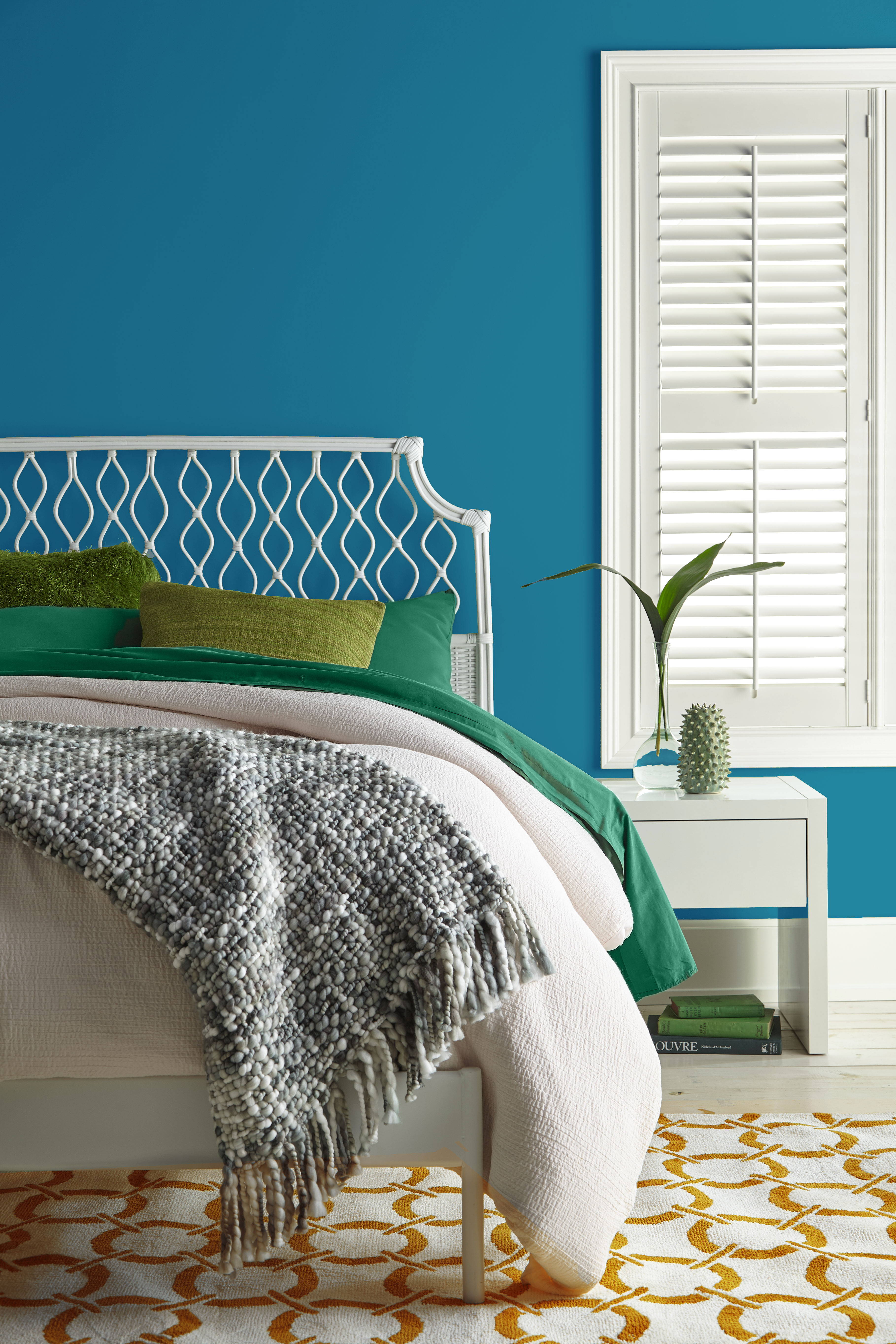 Cette image montre une chambre à coucher aux murs bleu foncé pur, avec de la literie verte et crème.